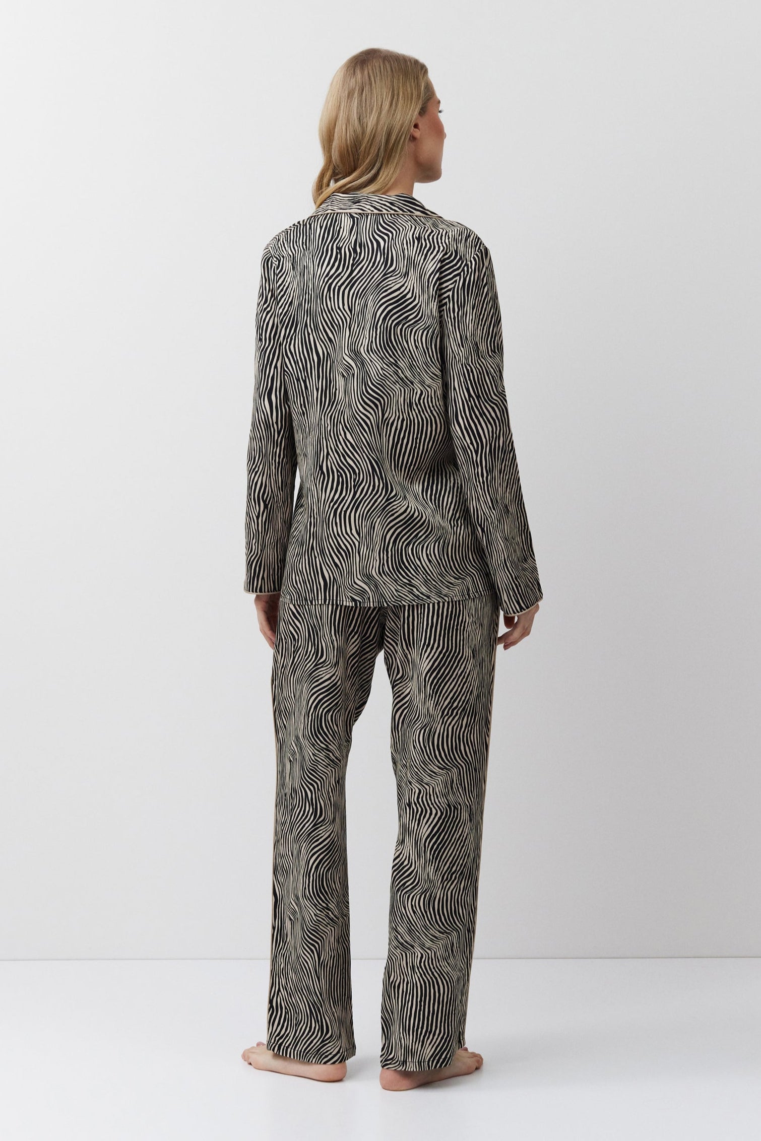 Woman wearing a patterned pajama set standing against a white background