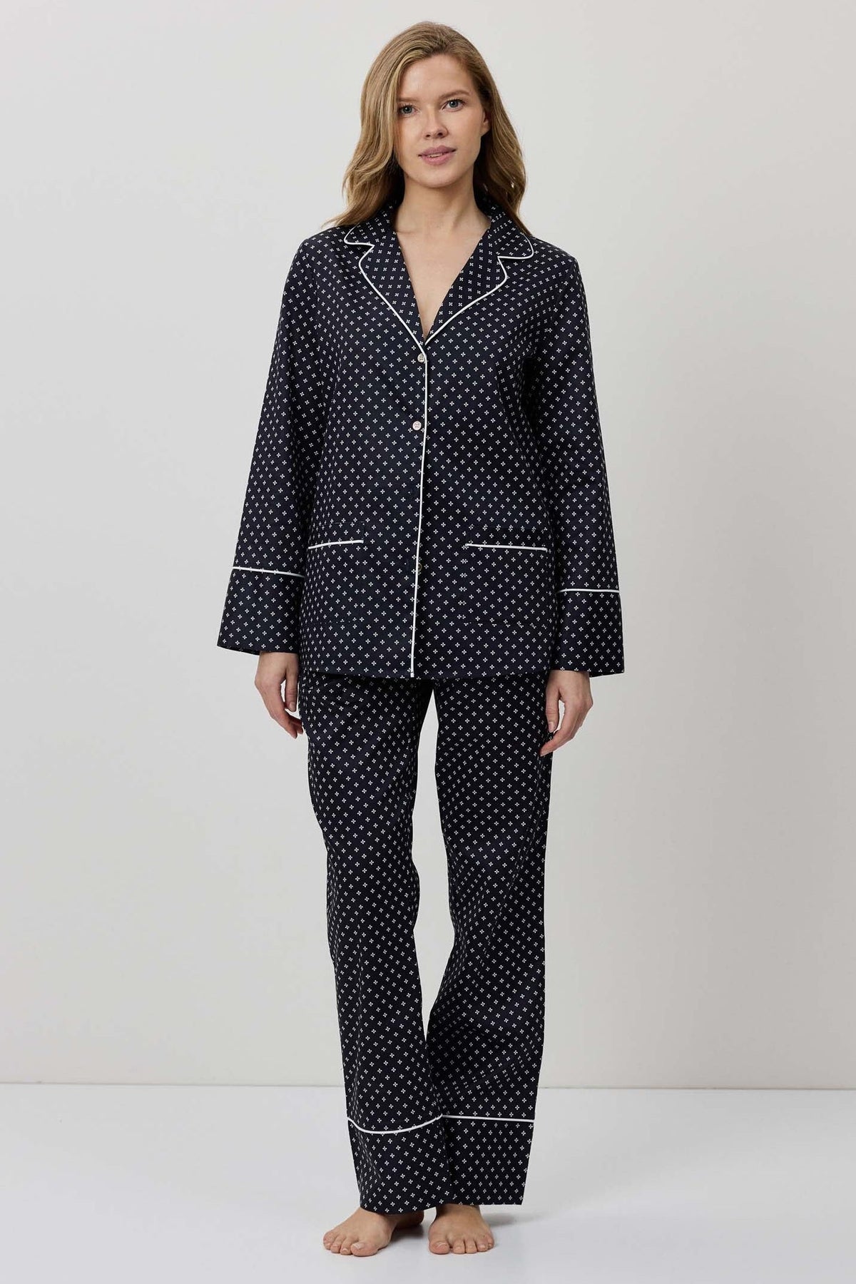 Woman wearing a black polka dot pajama set on a white background