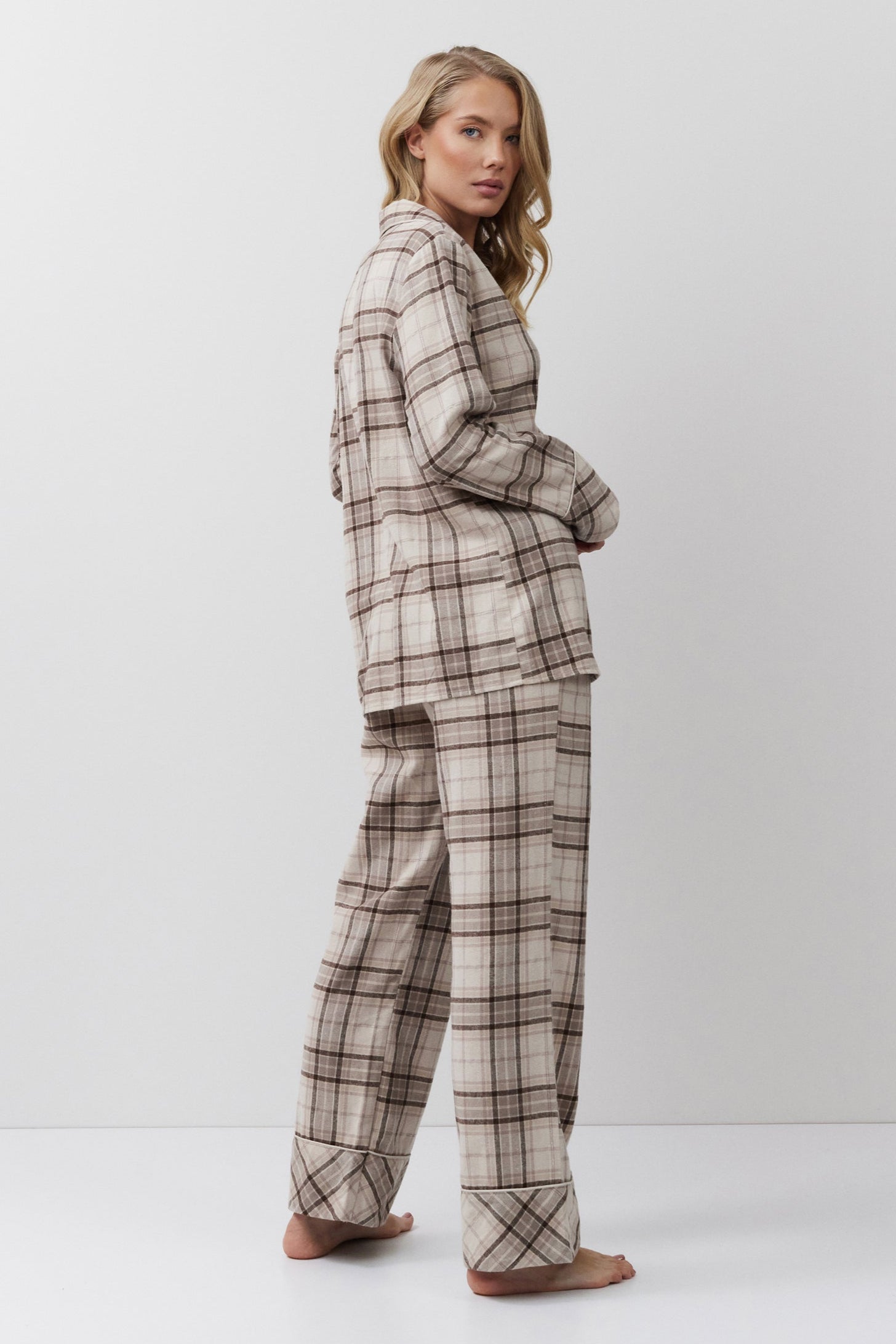 Person wearing a plaid pajama set on a white background