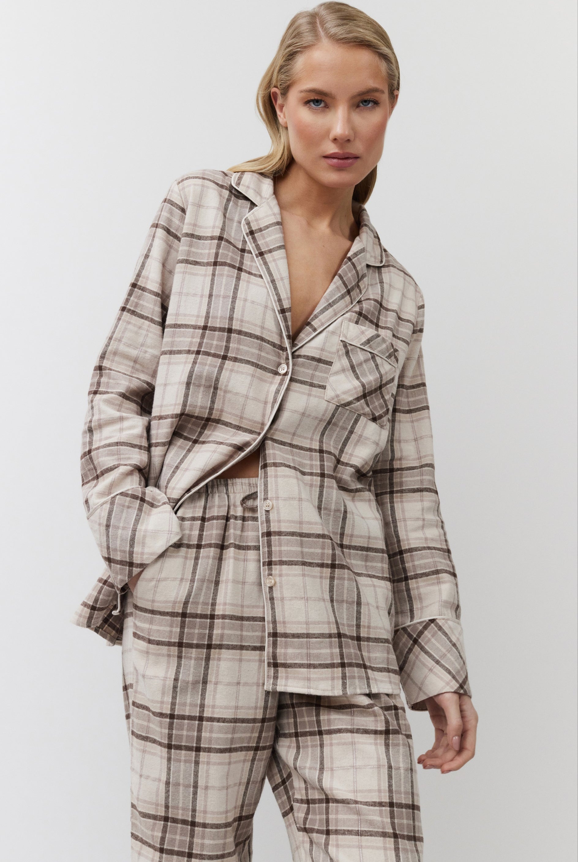 Woman wearing a plaid pajama set with pants against a plain background