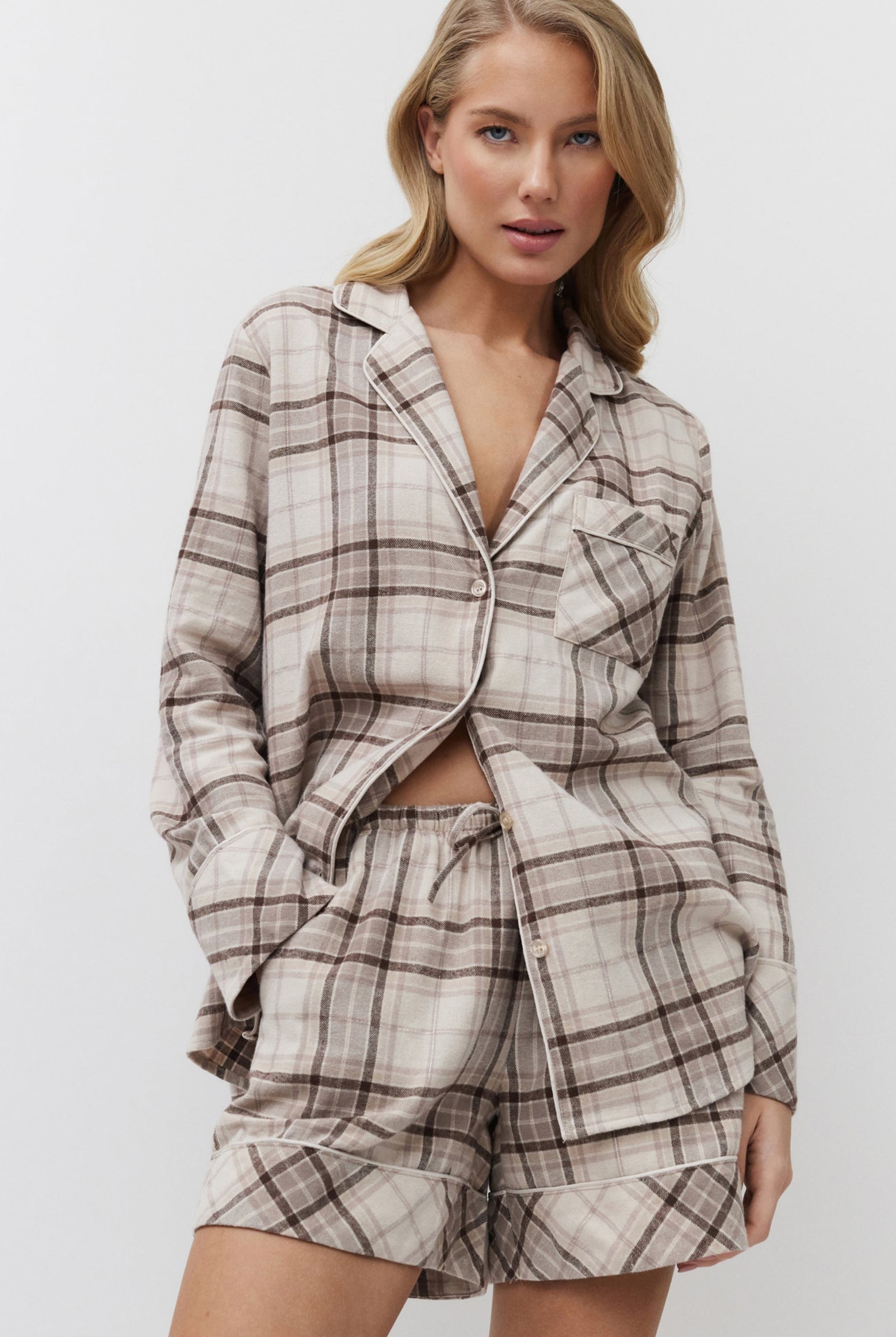 Woman wearing a plaid pajama set against a plain background