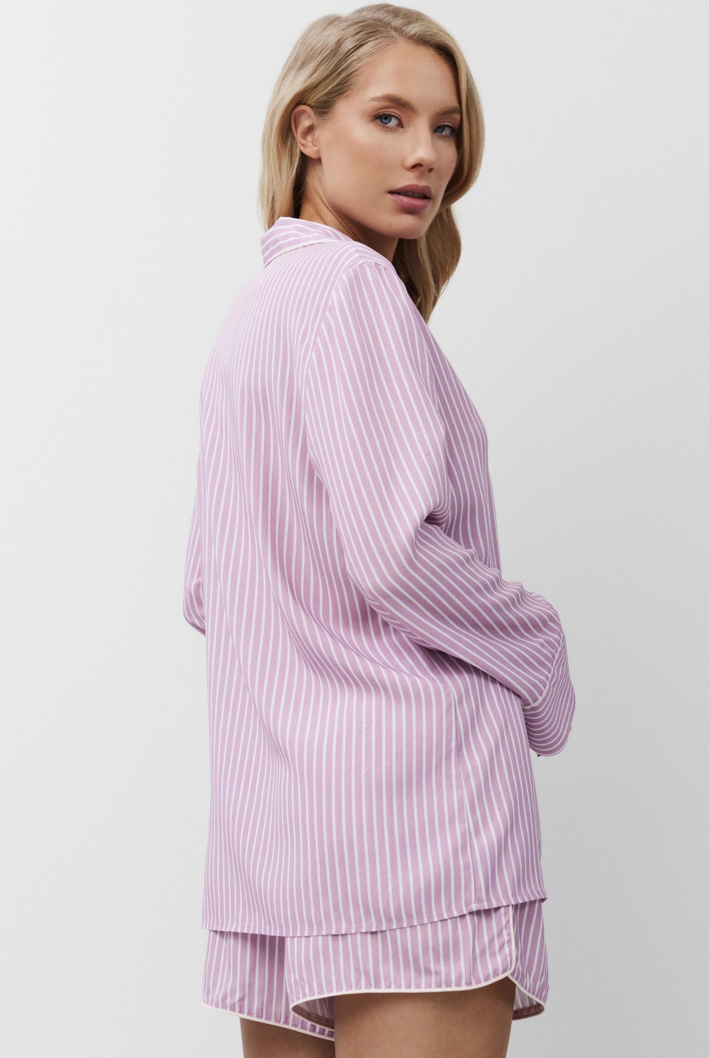 Woman wearing a lilac striped pajama set with shorts on a white background