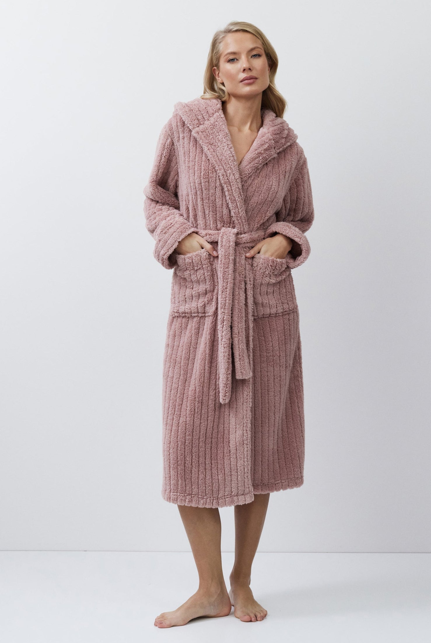 Woman wearing a pink bathrobe against a white background