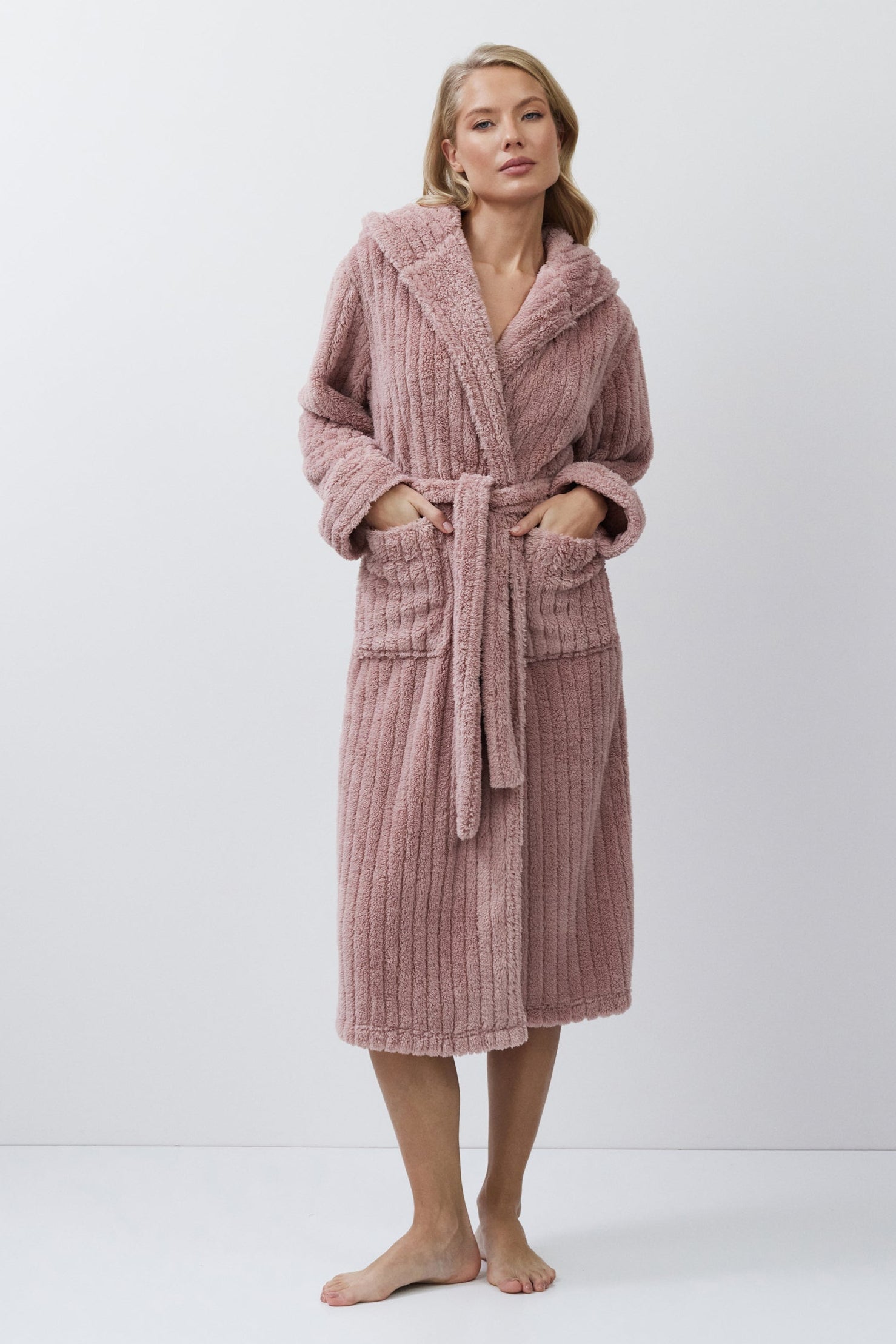 Woman wearing a pink bathrobe against a white background