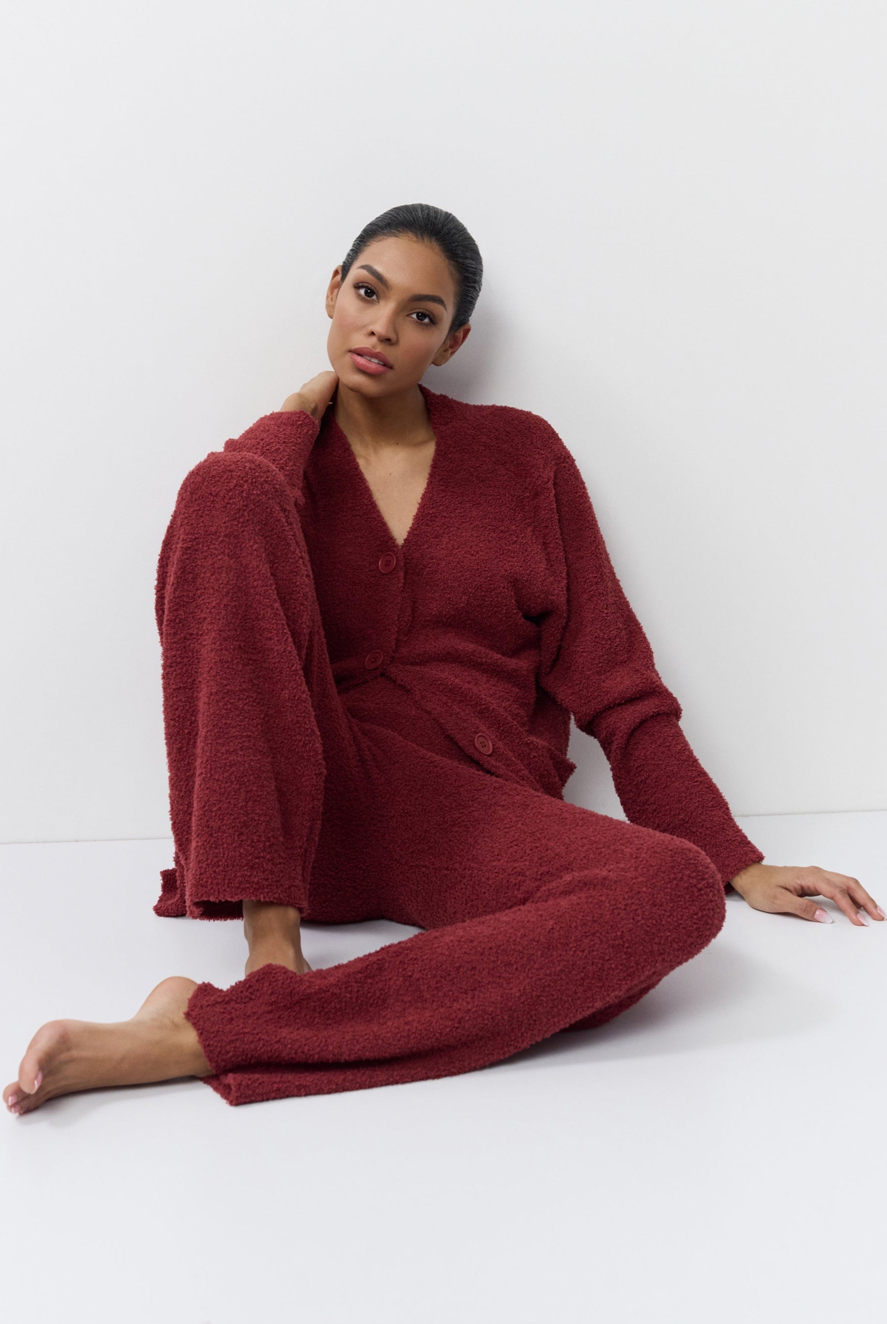 Woman wearing a red loungewear set sitting on a white floor.