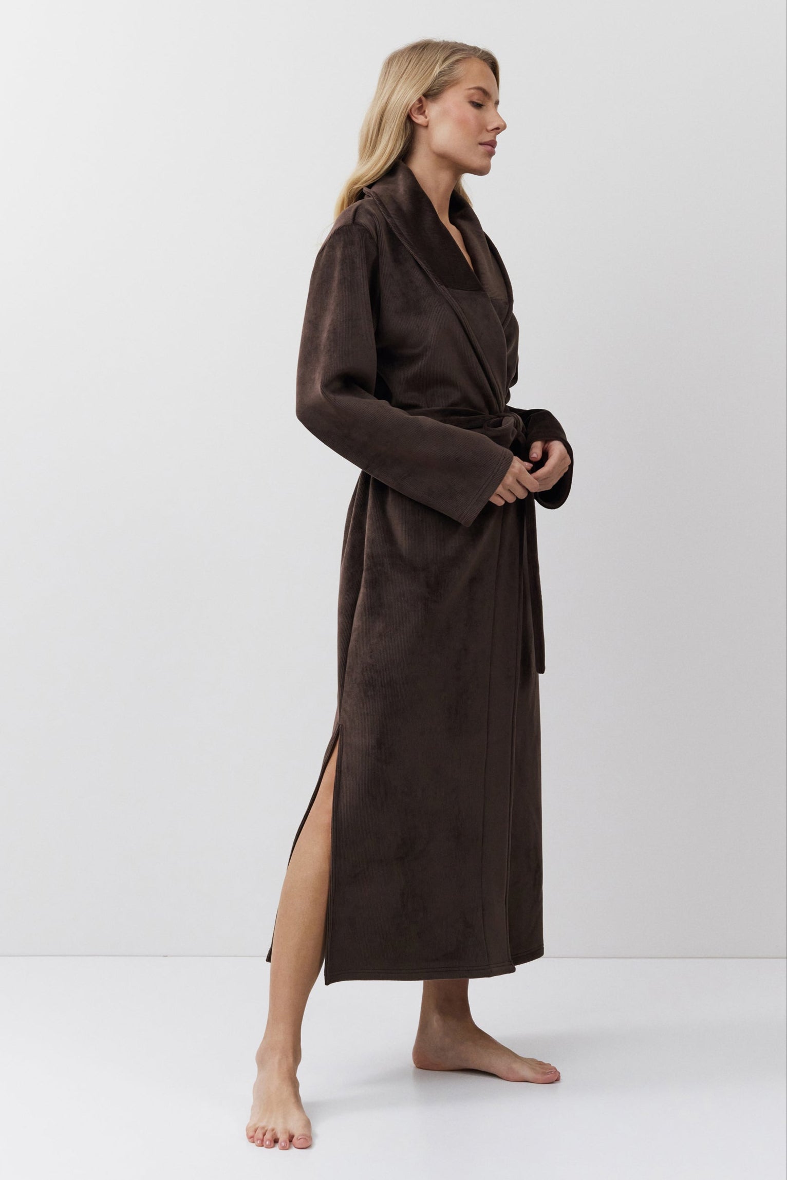 Woman wearing a brown bathrobe against a white background
