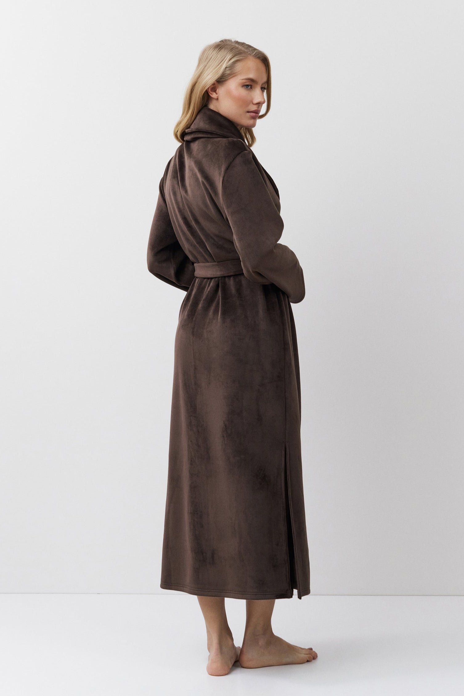 Woman wearing a brown bathrobe against a white background