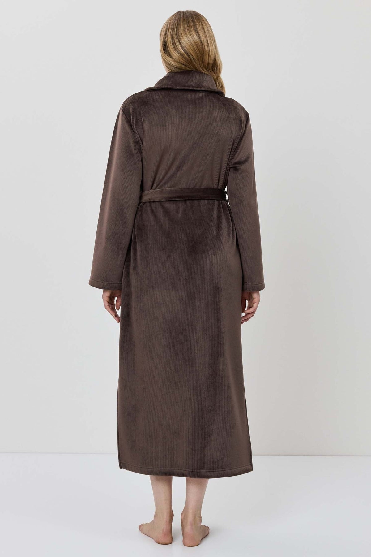 A woman wearing a long brown plush bathrobe with a tie belt.