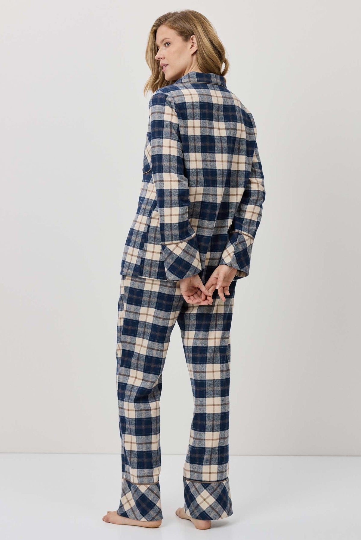 Woman wearing a blue and white plaid pajama set against a plain background