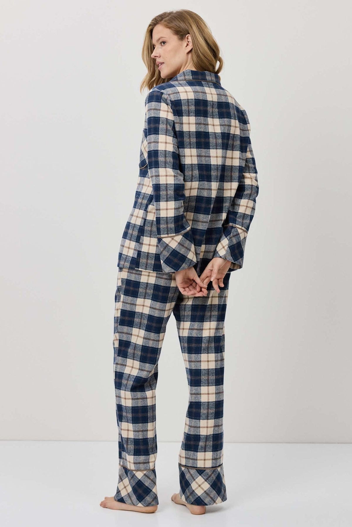 Woman wearing a blue and white plaid pajama set against a plain background