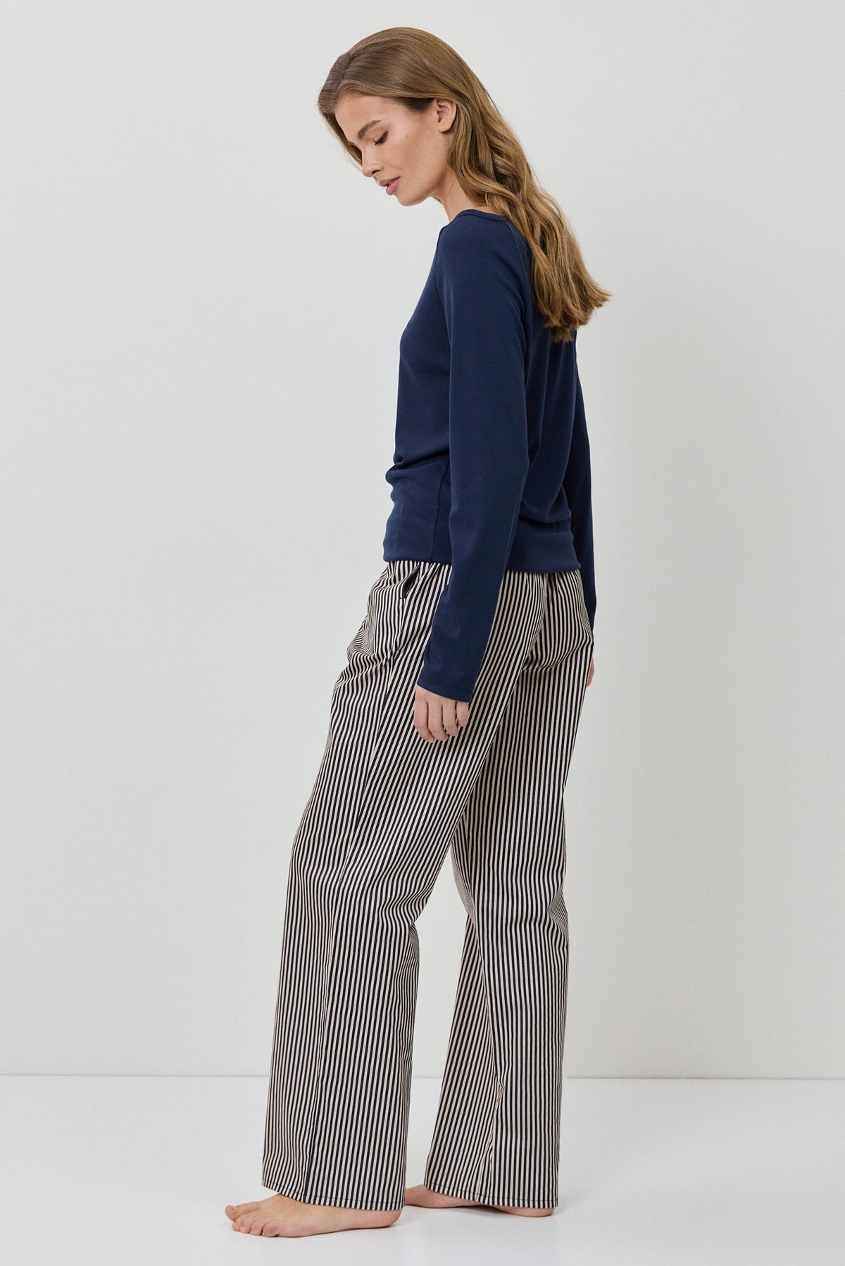 Woman wearing a navy sweater and gray checkered pants on a white background