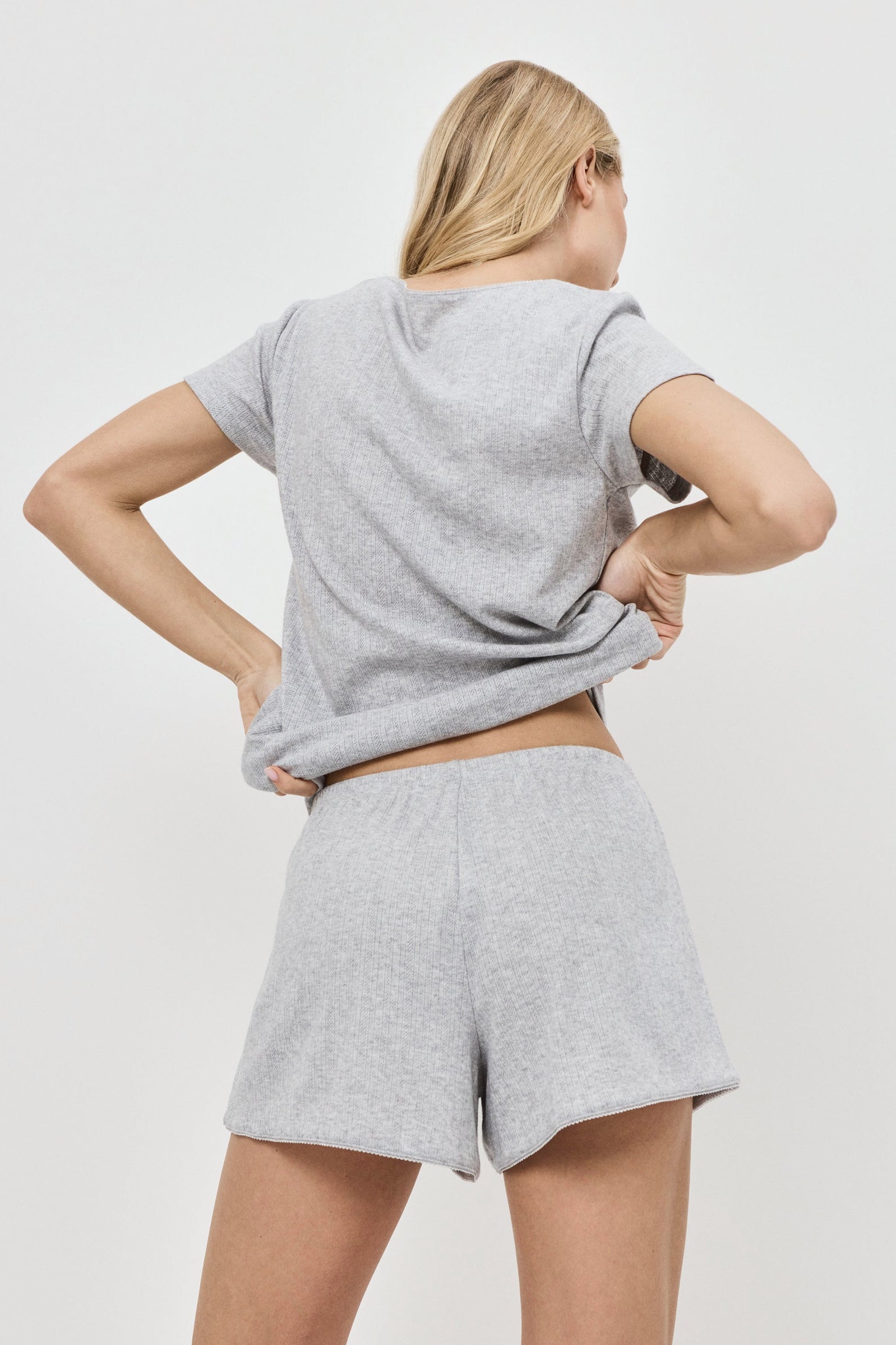 Person wearing a gray pajama set with shorts set on a white background