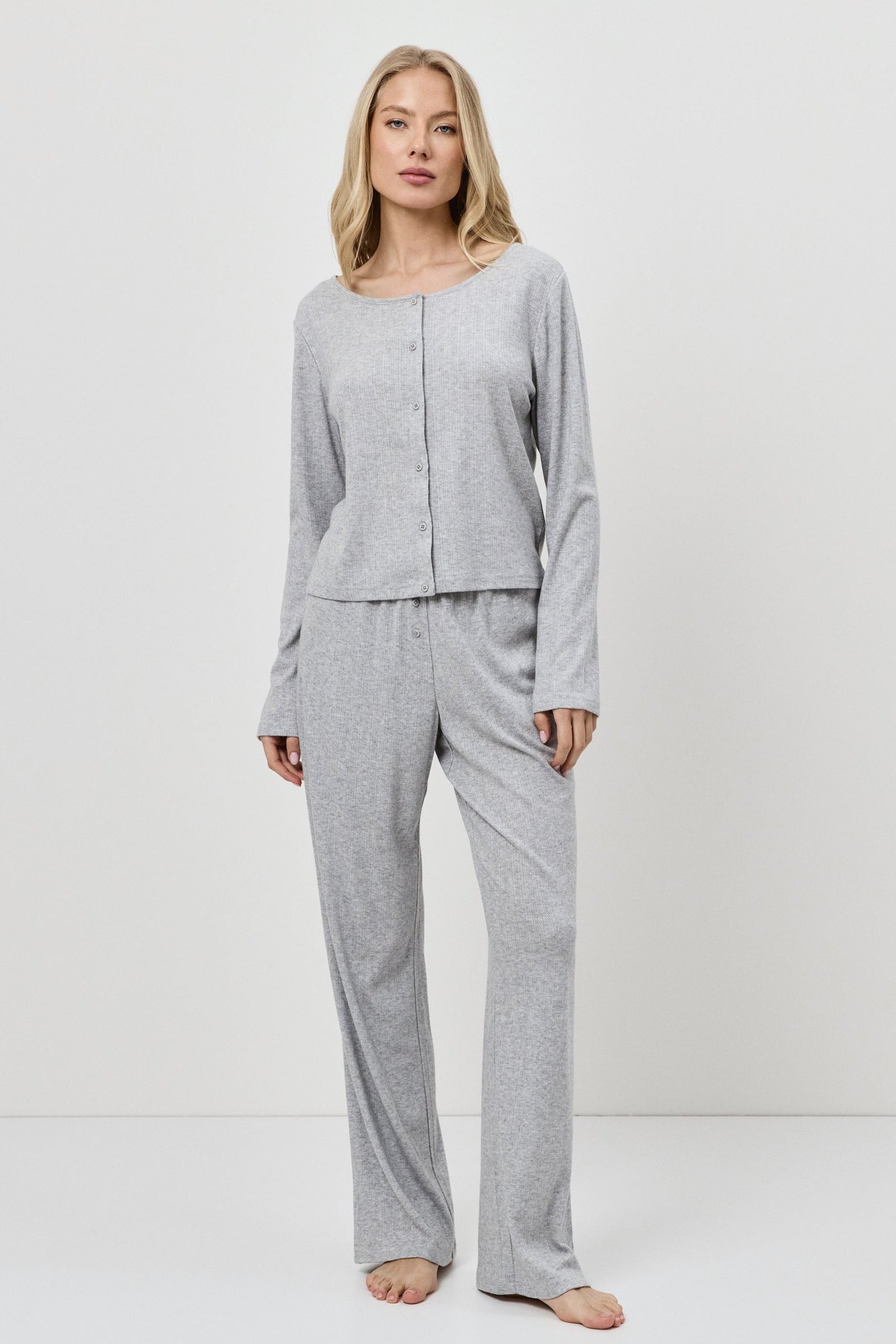 Woman wearing a gray pajama set against a white background