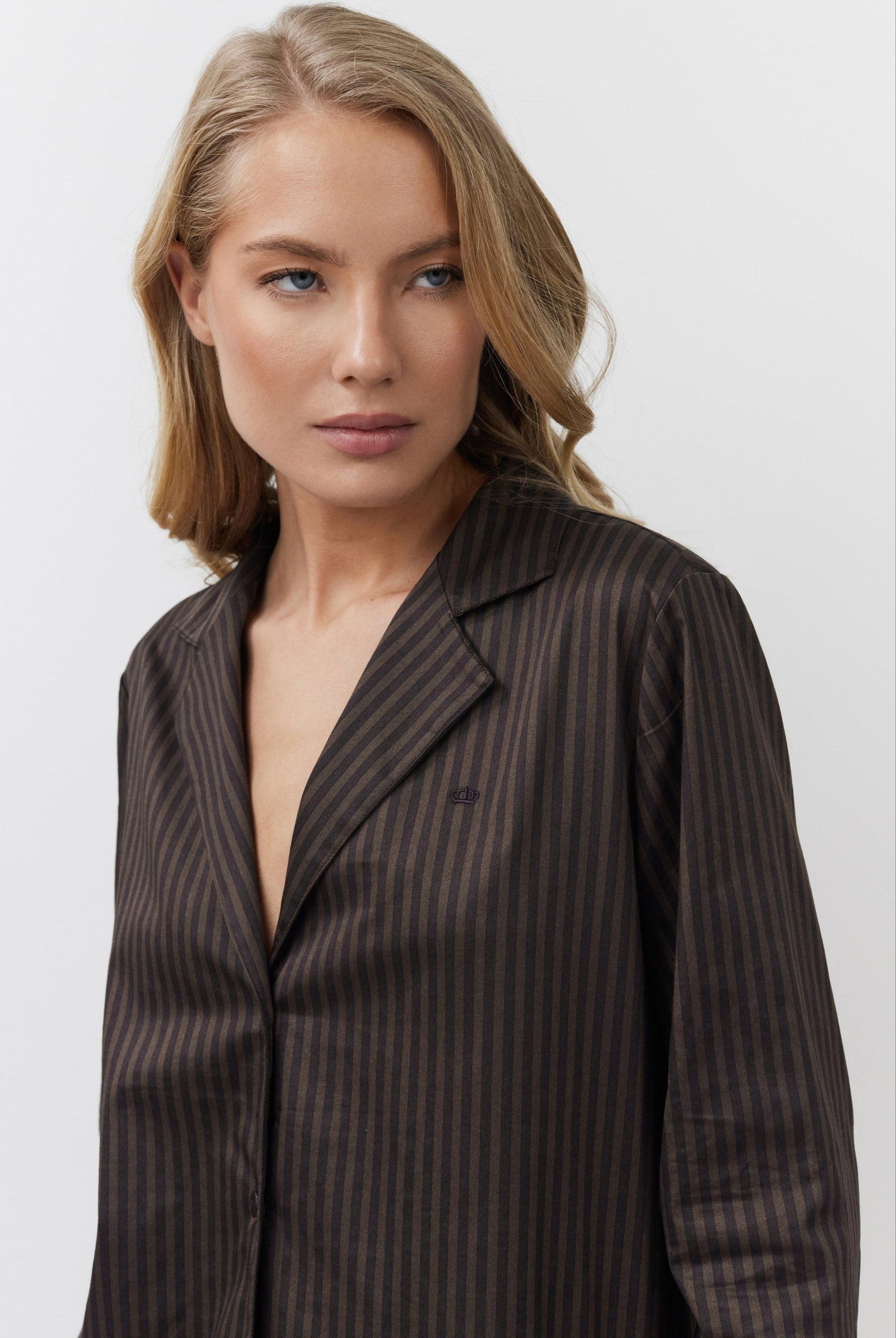 Woman wearing a brown pinstripe shirt against a white background