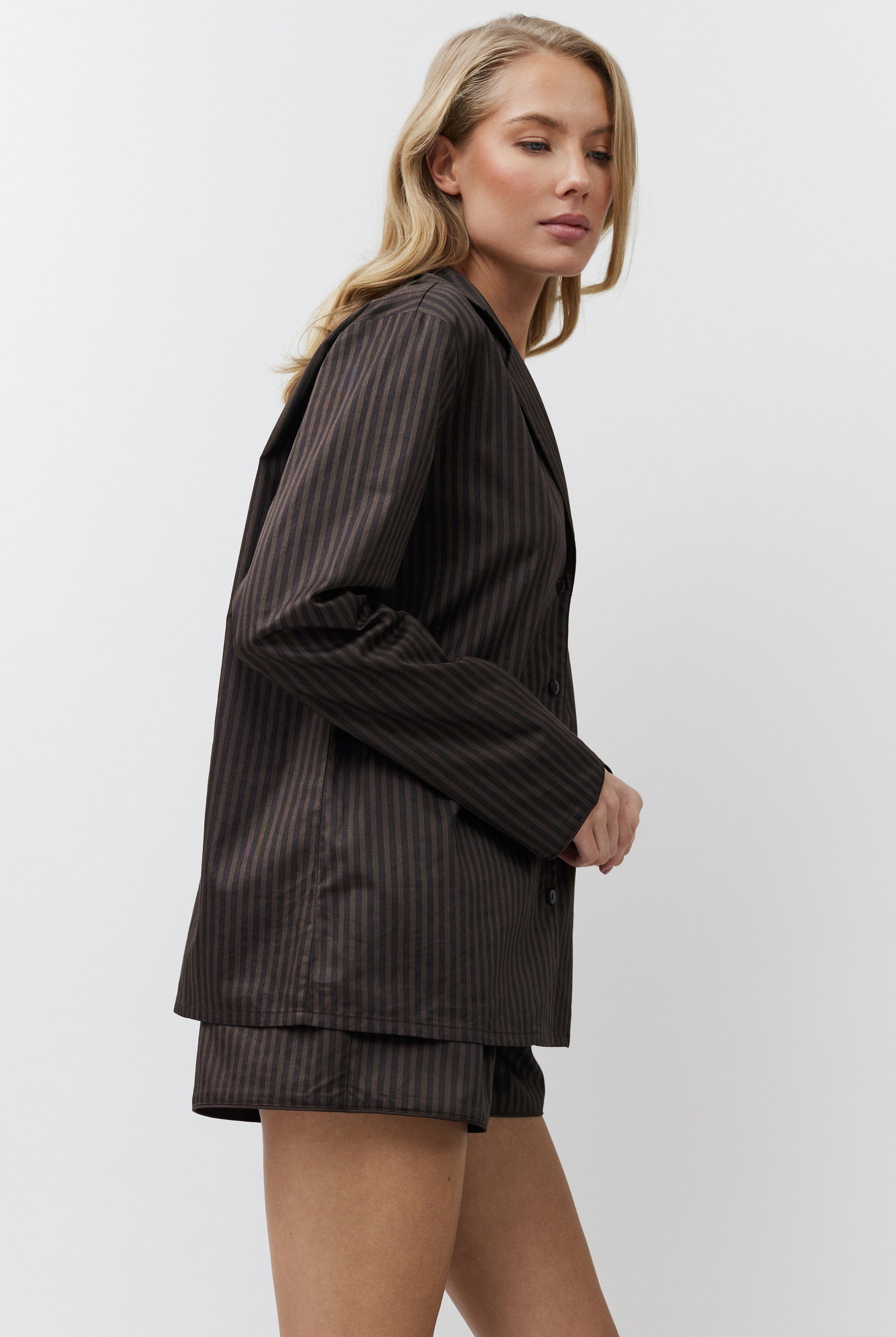 Woman wearing a brown pajama set on a white background