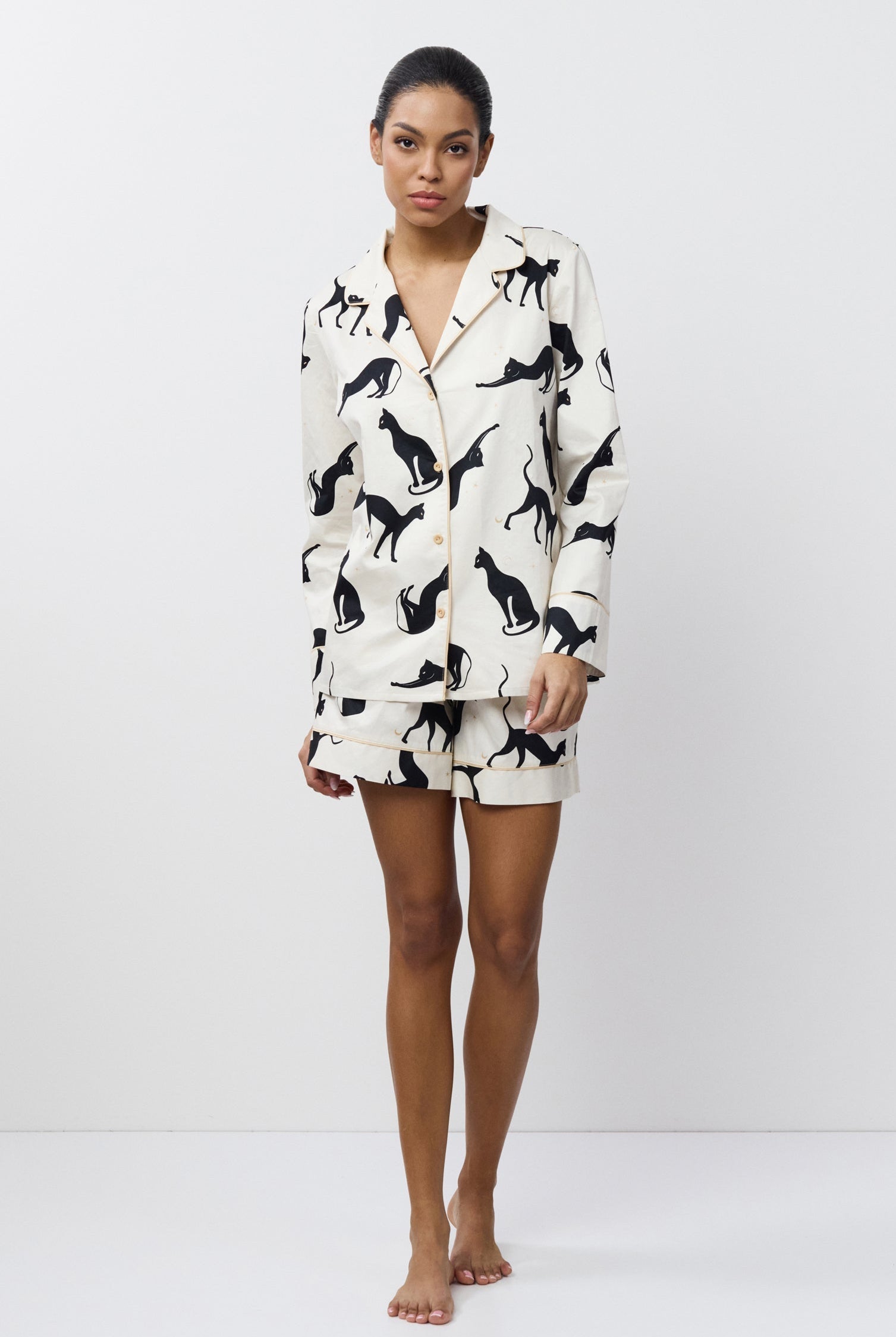 Person wearing a white pajama set with black cat prints on a white background