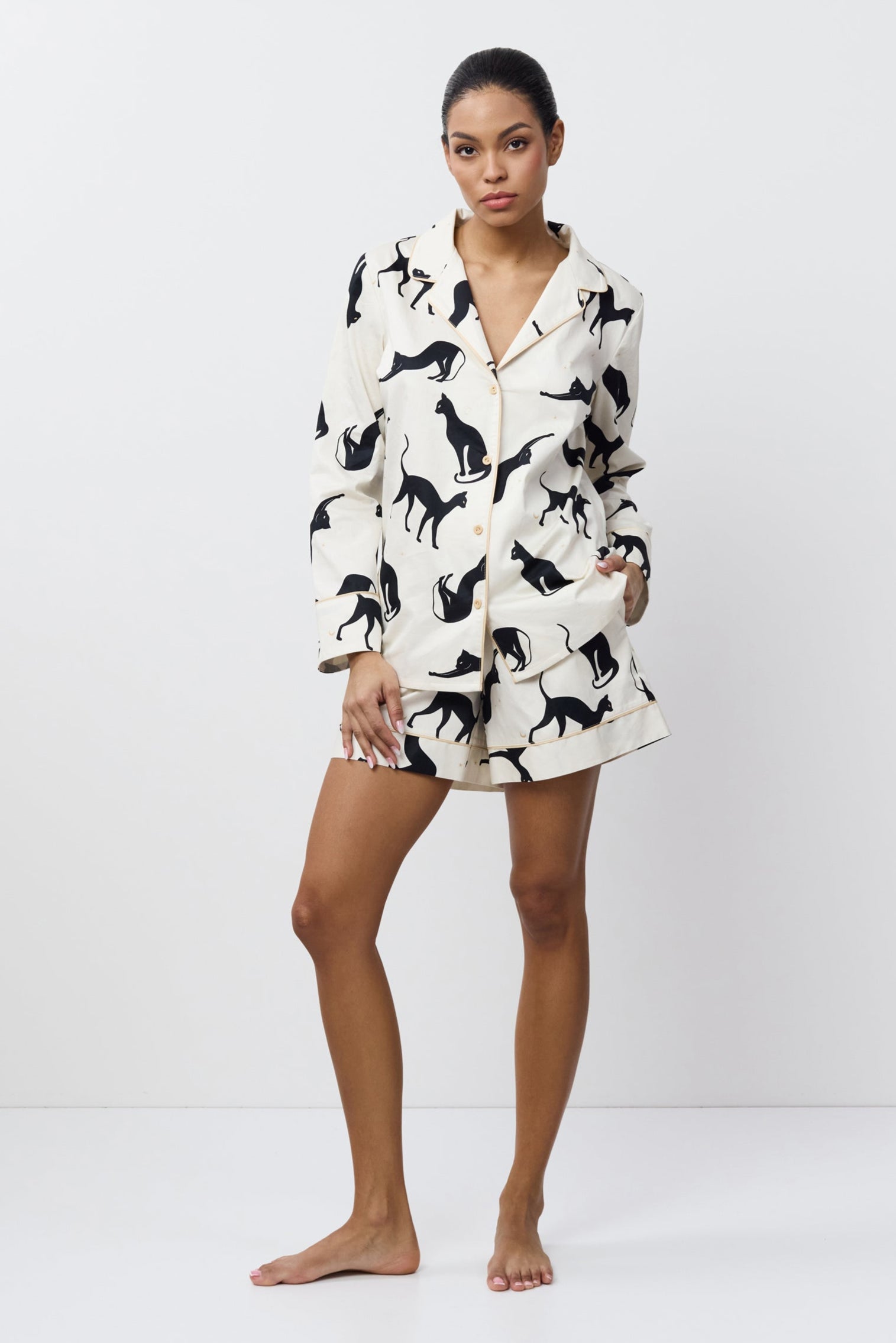 Woman wearing a pajama set with cat pattern on a white background