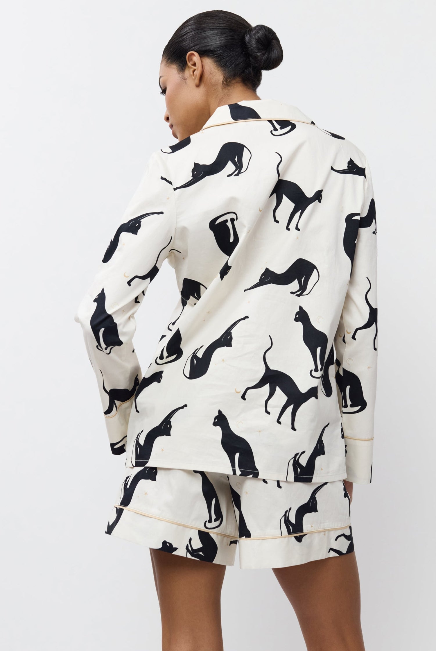 Person wearing a pajama set with shorts with black animal prints on a white background