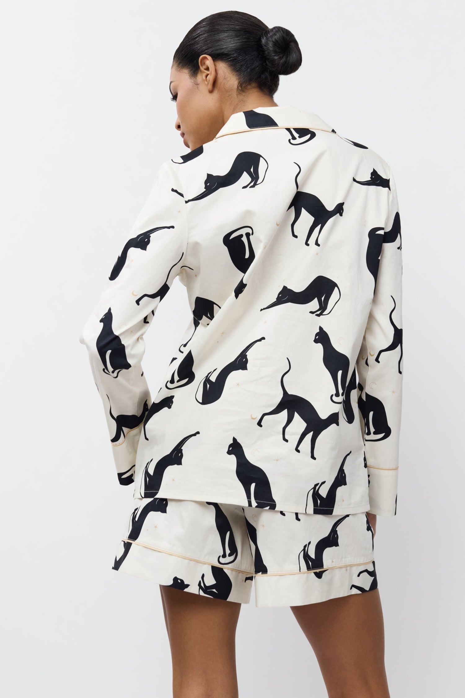 Person wearing a pajama set with shorts with black animal prints on a white background