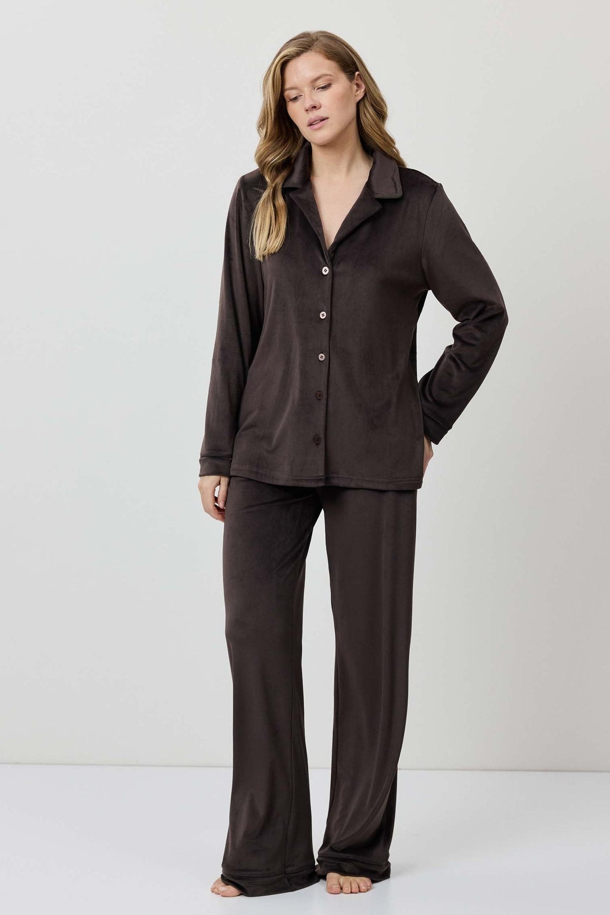 Woman wearing a brown pajama set against a white background