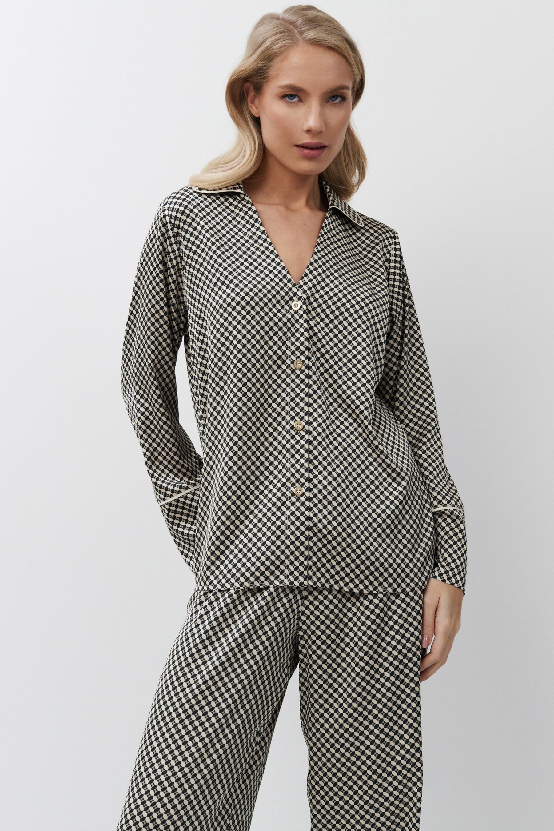 Woman wearing a checkered shirt and pajama pants on a white background