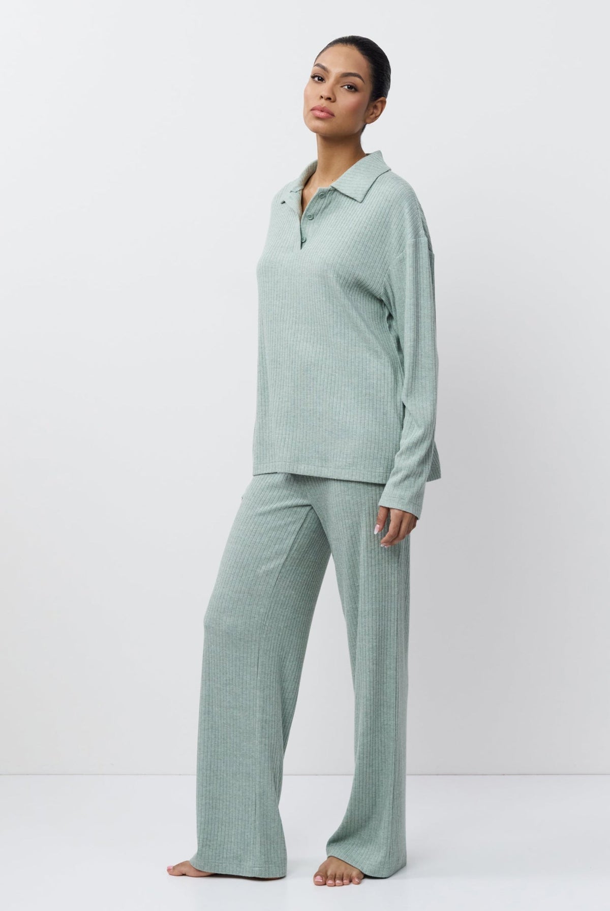 Woman wearing a light green pajama set against a white background
