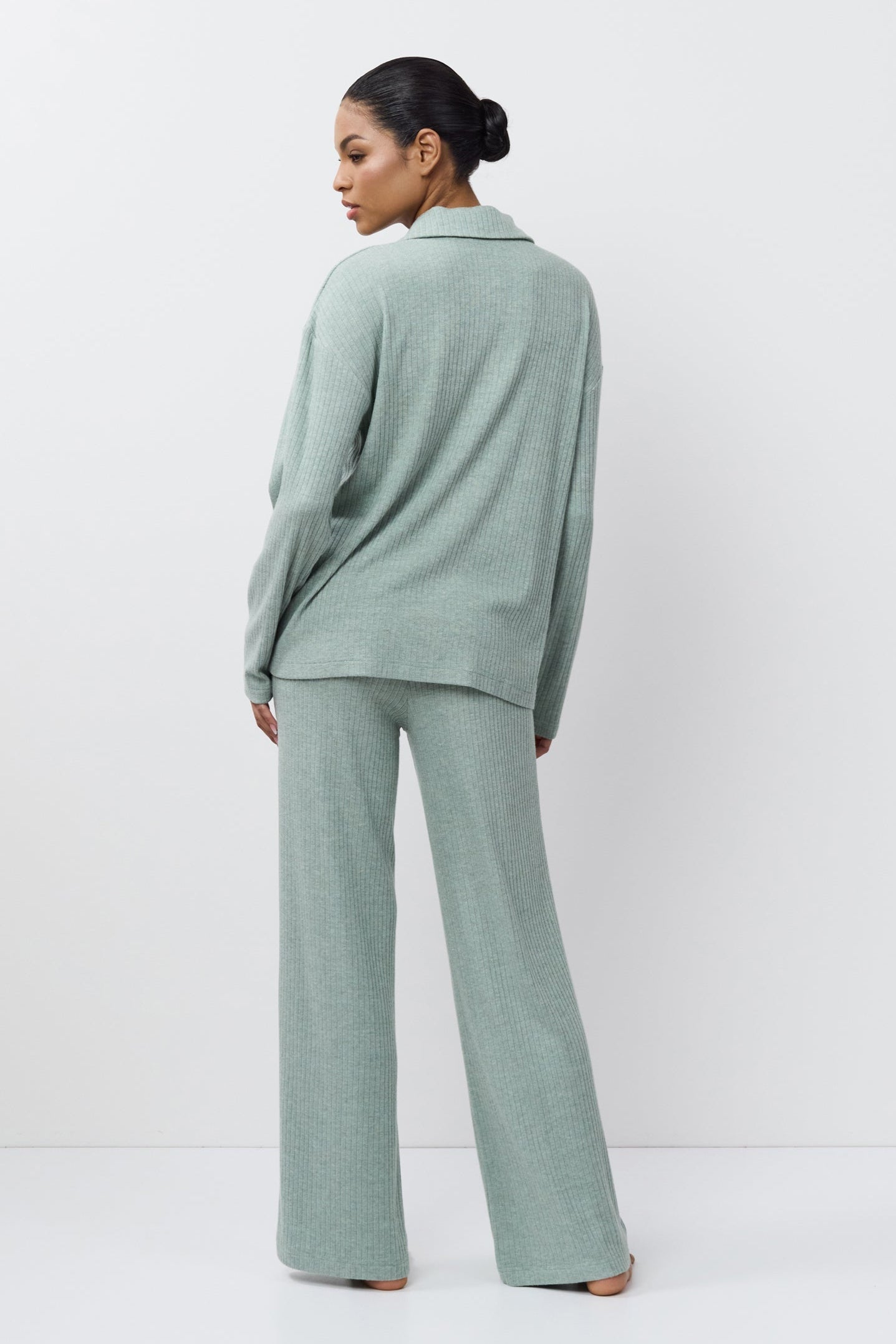 Person wearing a light green outfit standing against a white background