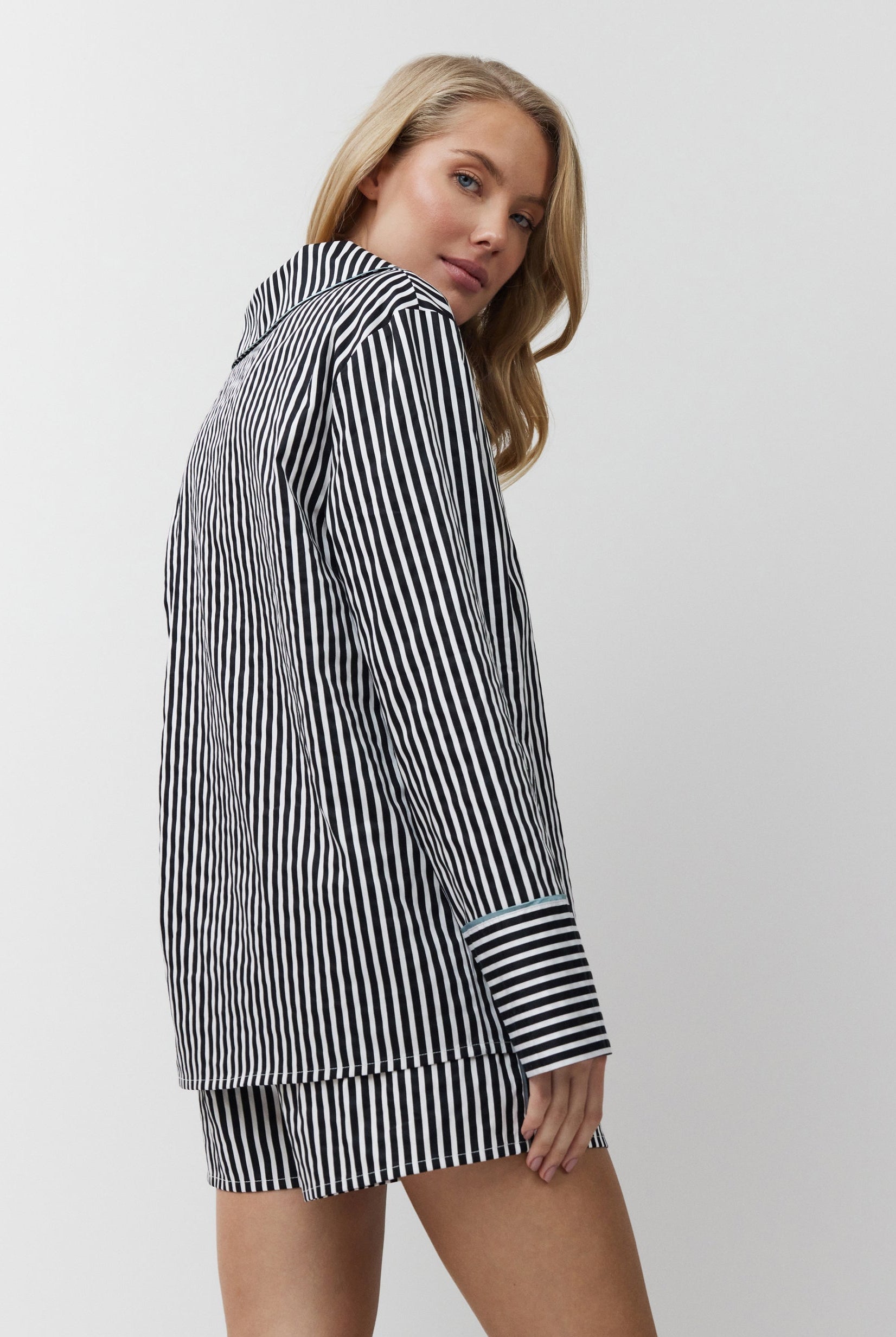 Woman wearing a black and white striped shirt dress on a plain background