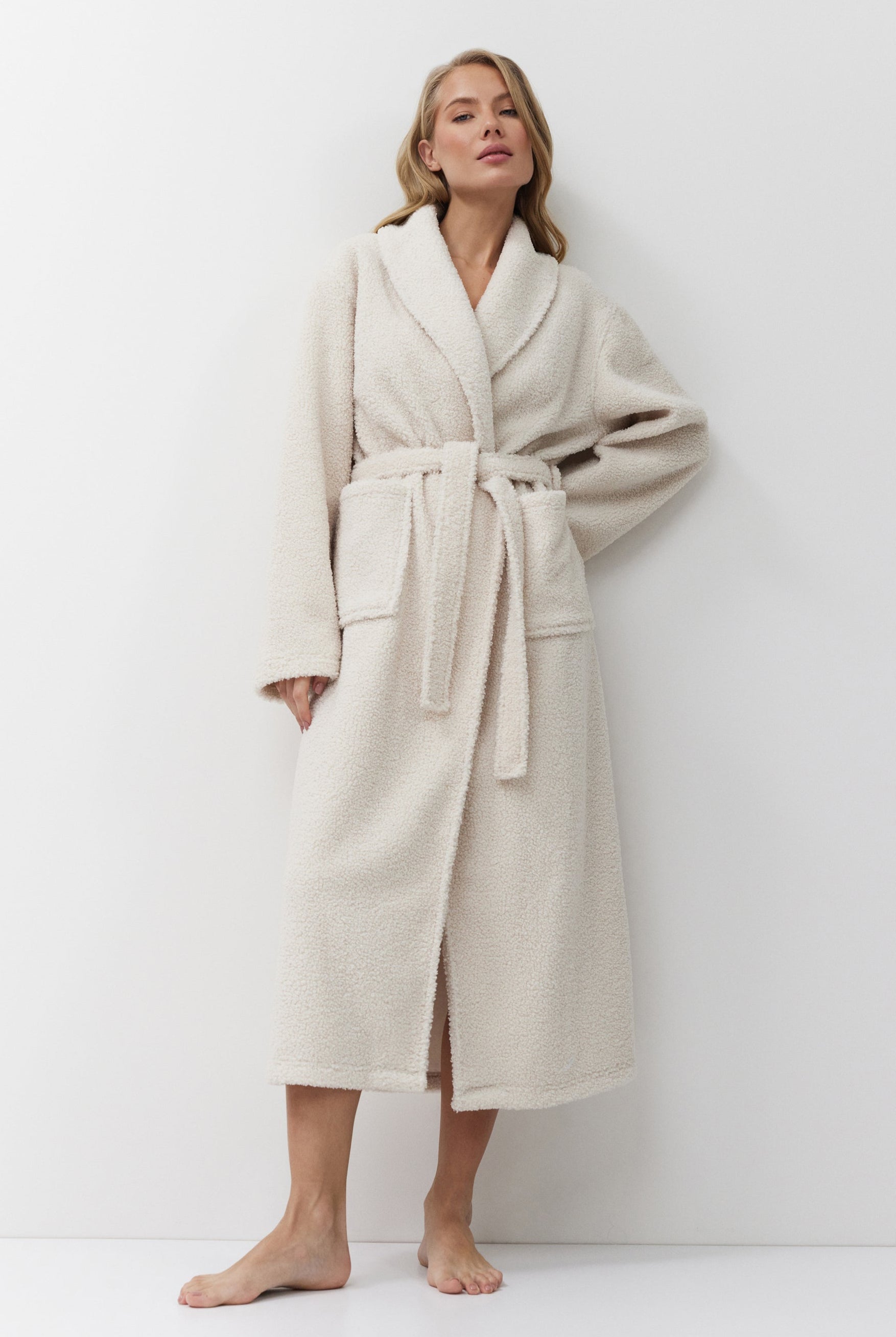Woman wearing a beige bathrobe against a white background