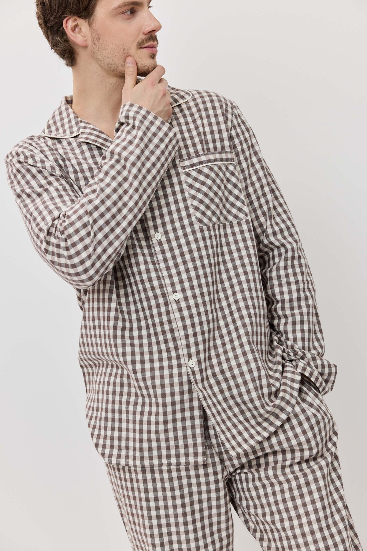 Man wearing a brown and white checkered pajama set against a plain background