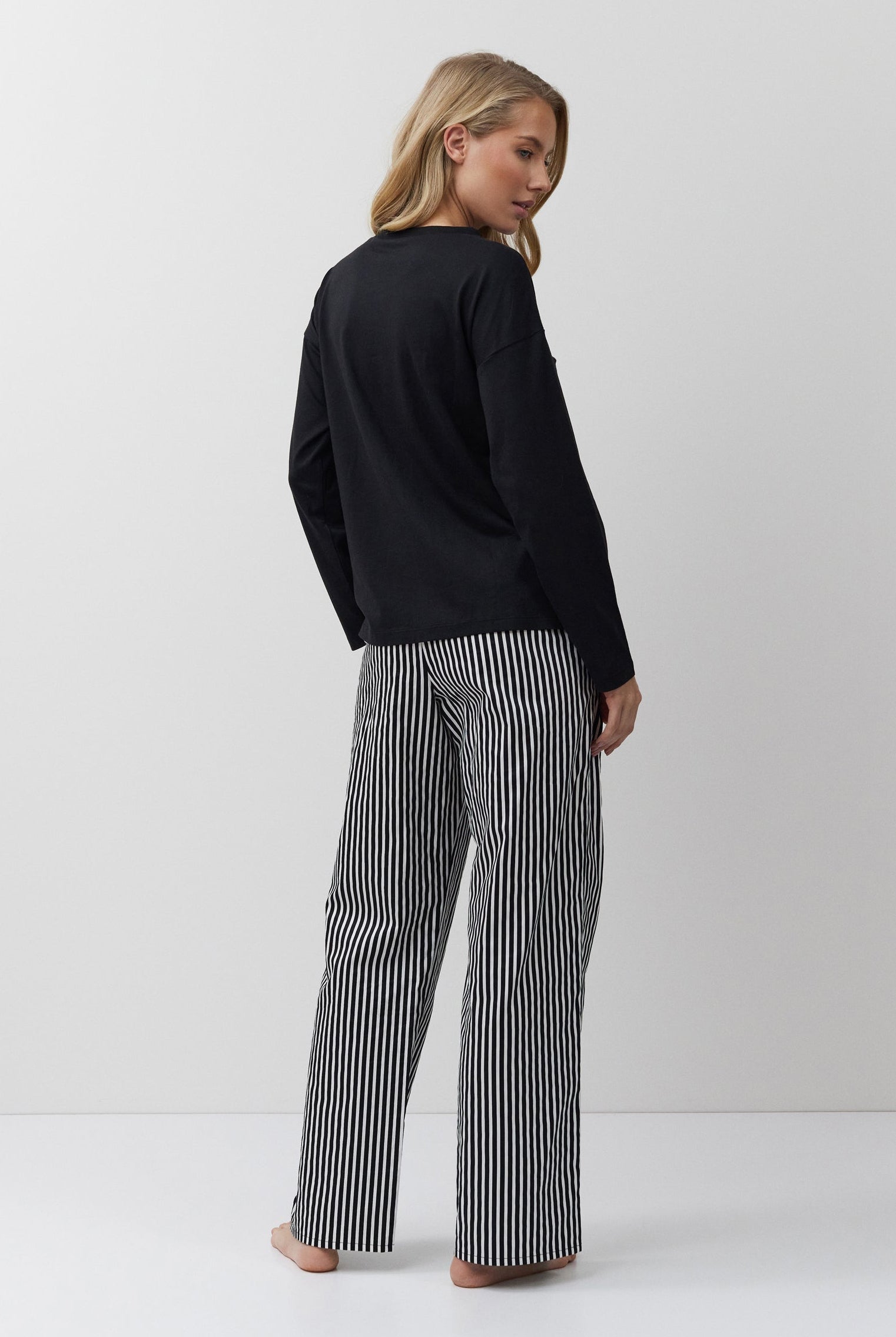 Woman wearing a black sweater and striped pants on a white background