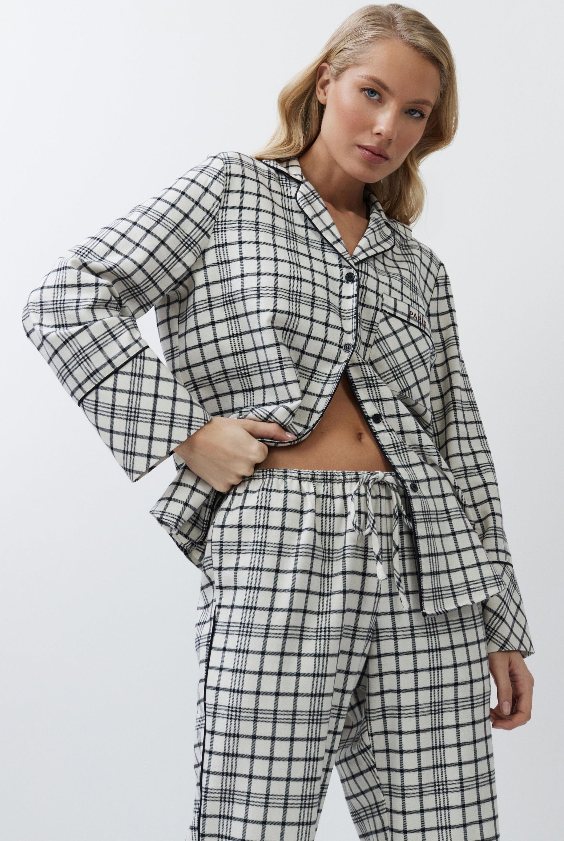Woman wearing a black and white checkered pajama set on a plain background