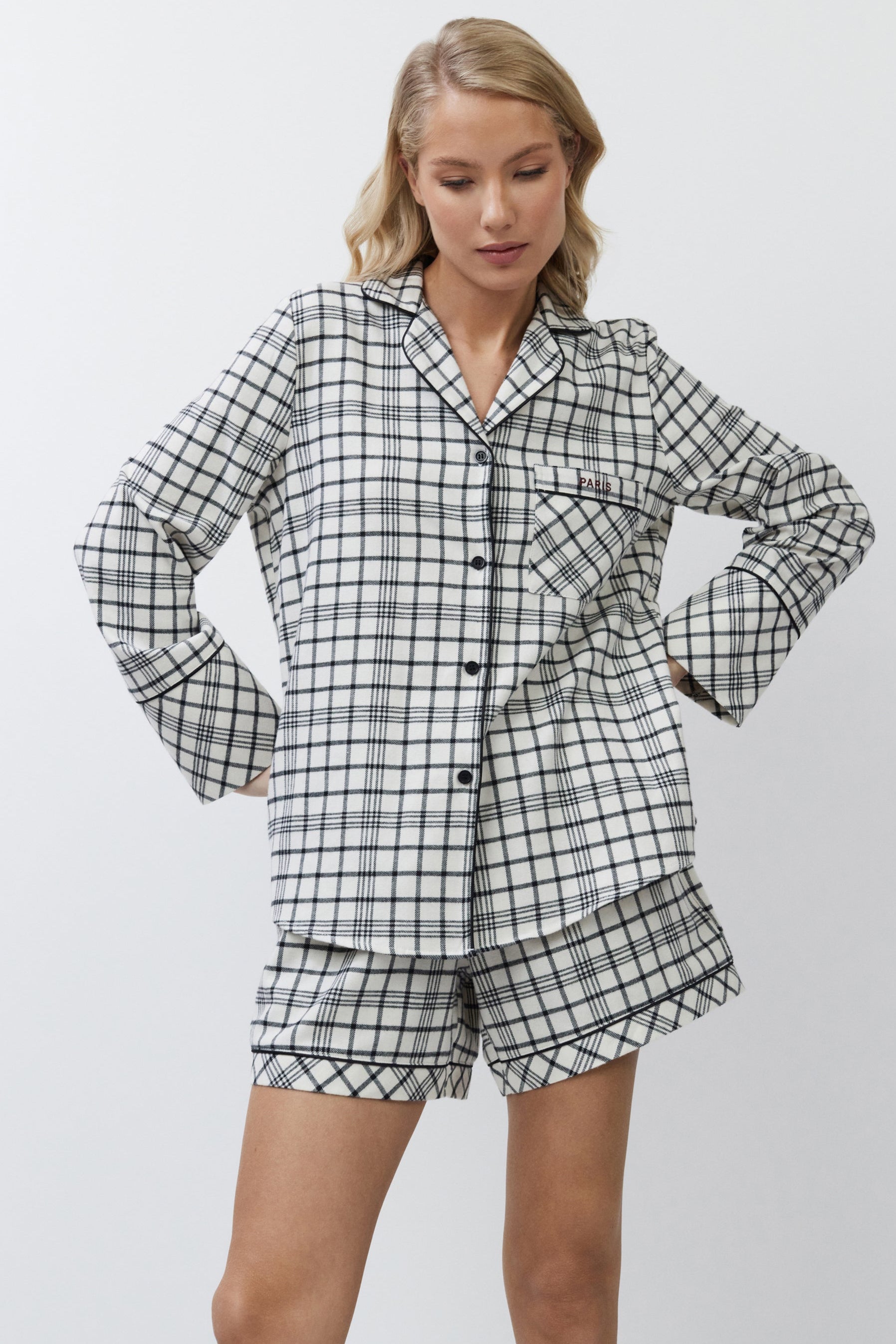 Woman wearing a black and white checkered pajama set on a plain background