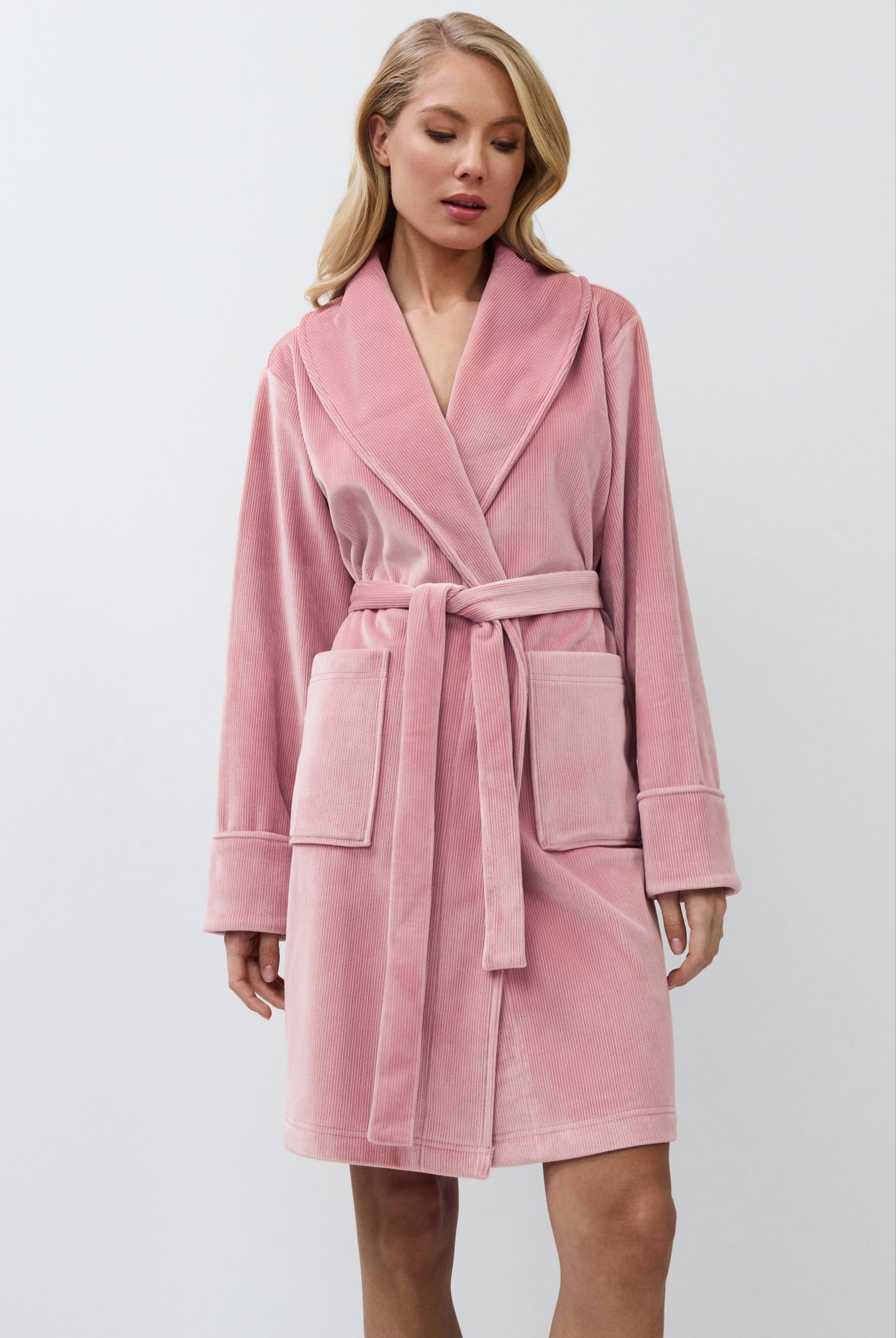 Woman wearing a pink bathrobe against a white background