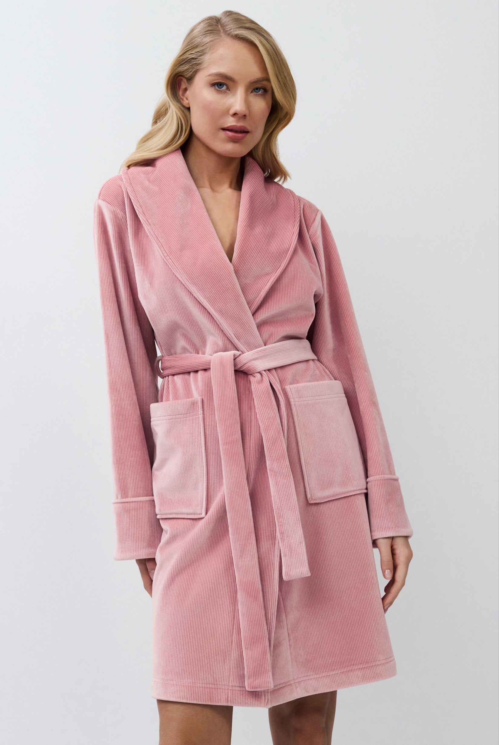 Woman wearing a pink bathrobe against a white background