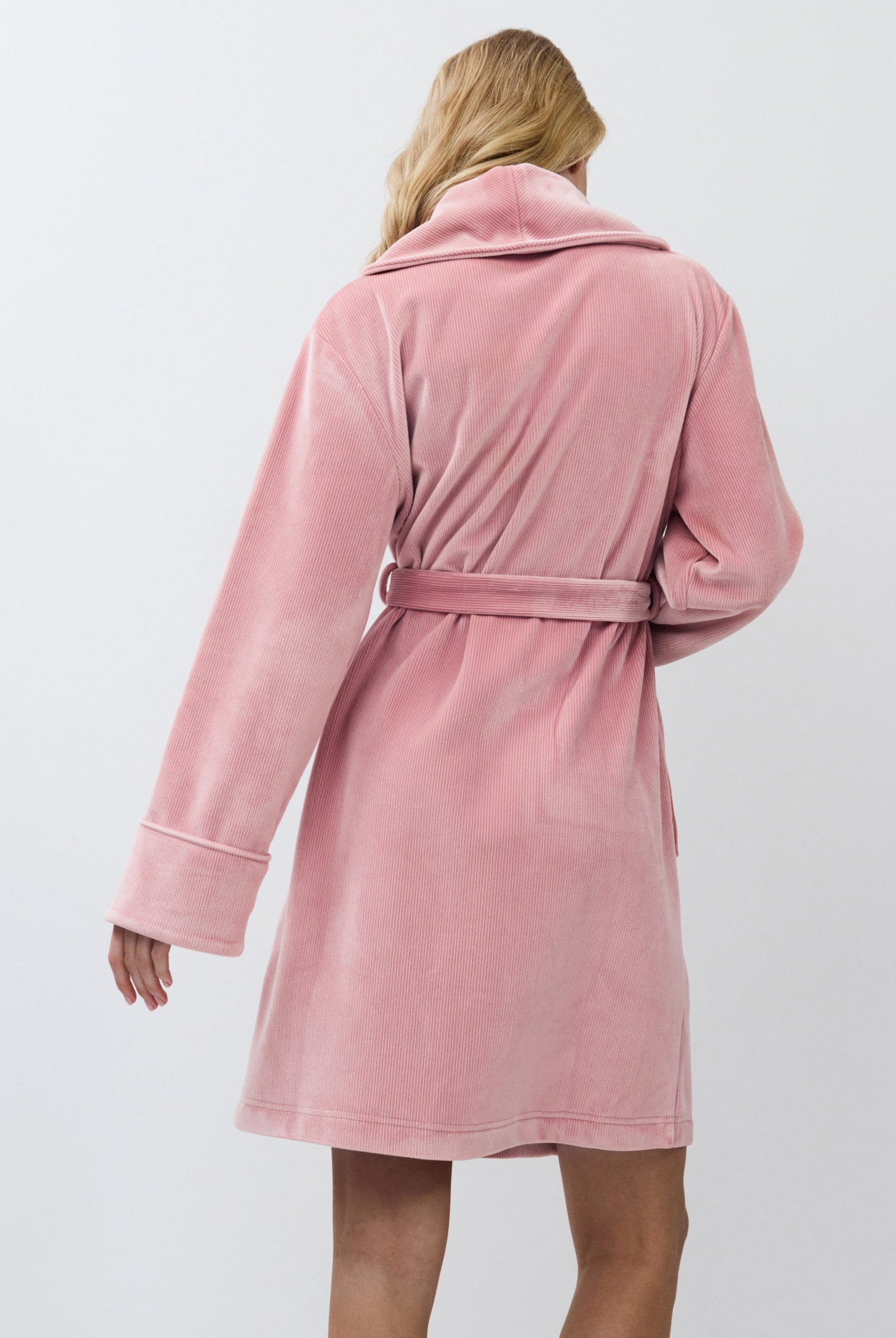 Person wearing a pink bathrobe against a white background