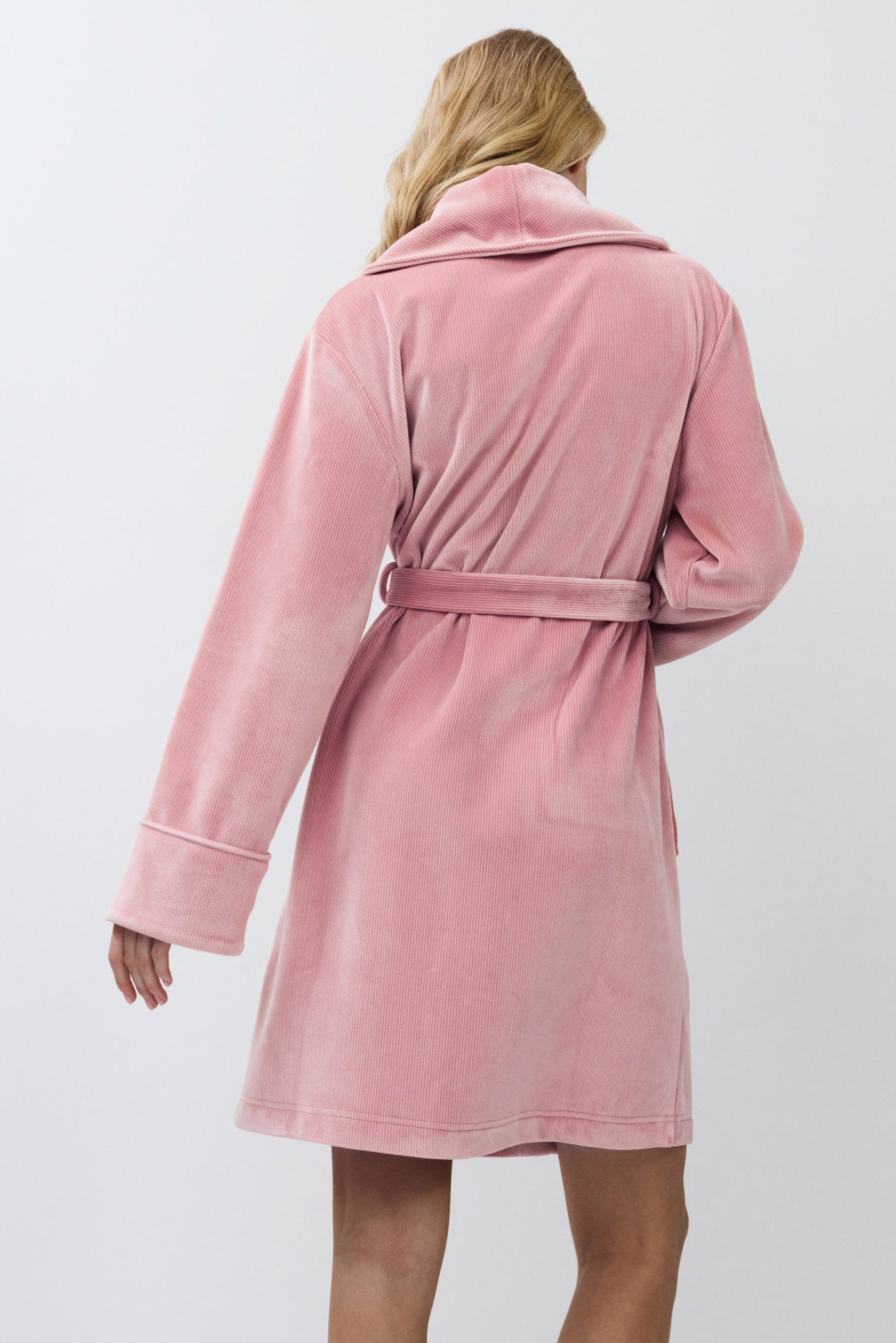 Person wearing a pink bathrobe against a white background
