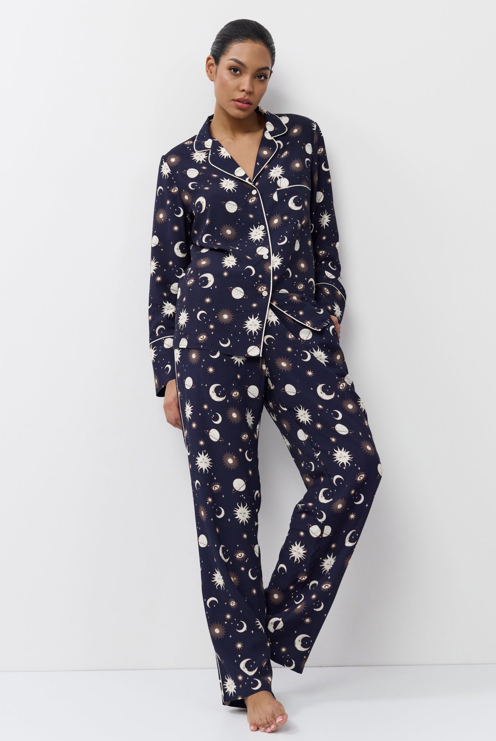 Woman wearing a navy blue pajama set with pattern on a white background