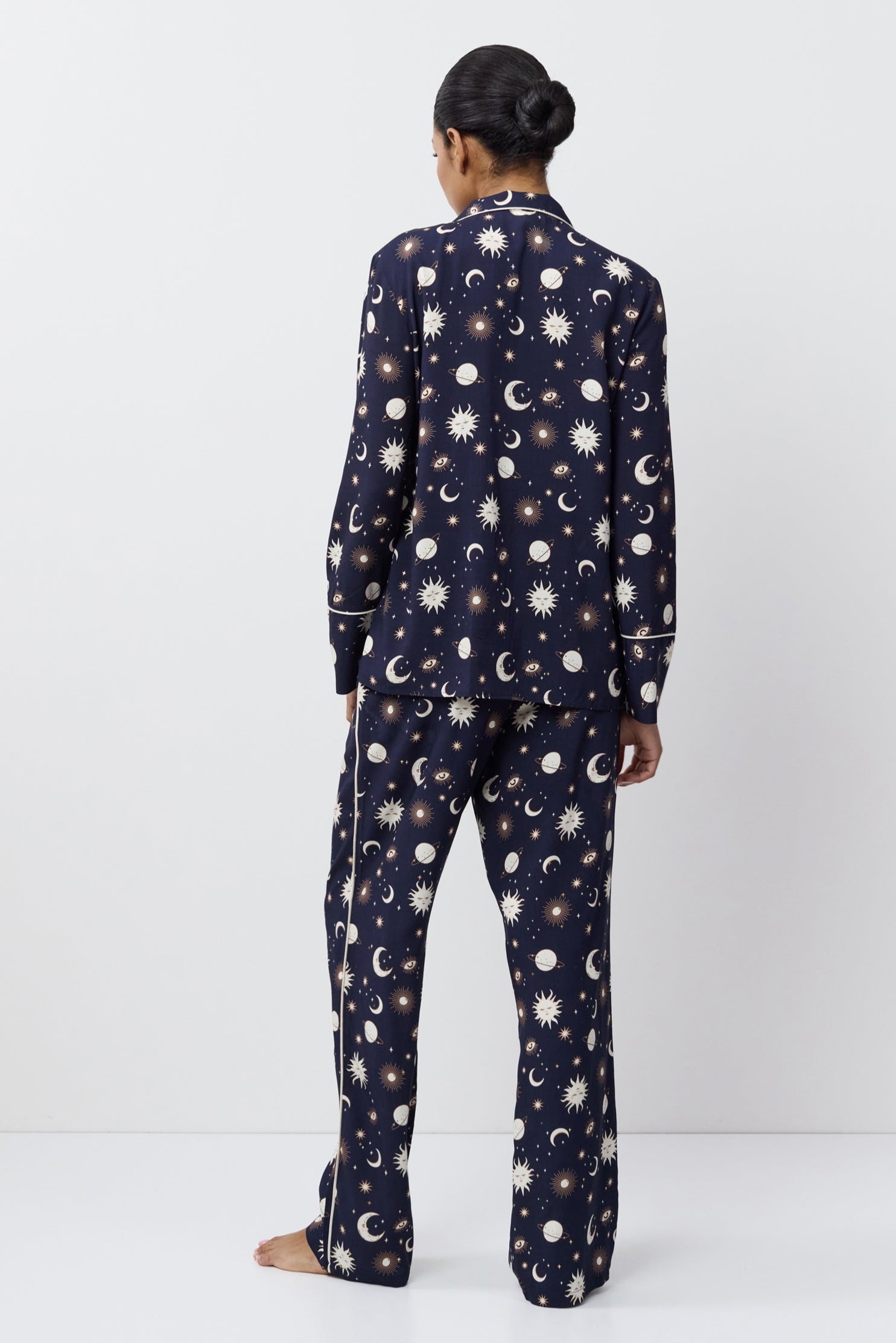 Person wearing a navy blue pajama set with pattern on a white background