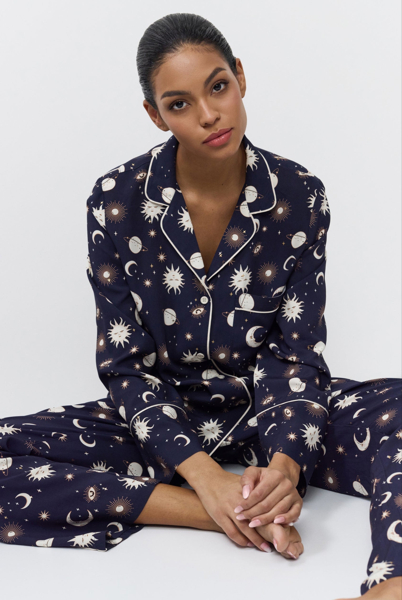 Woman wearing a navy blue pajama set with pattern on a white background