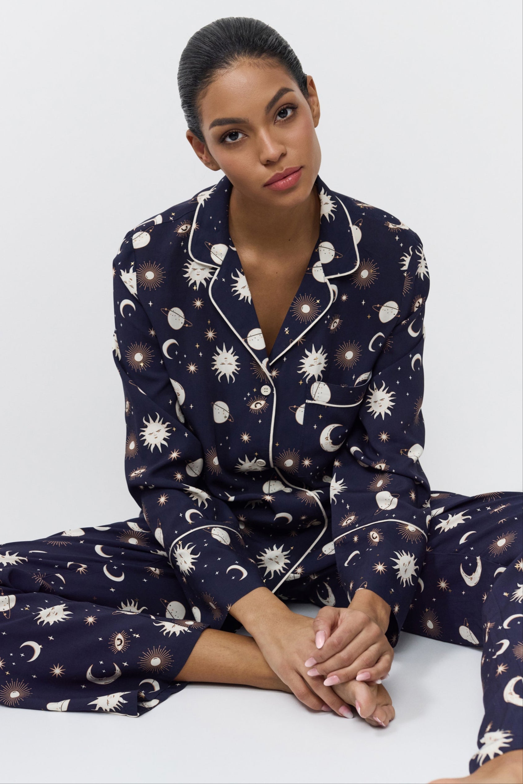 Woman wearing a navy blue pajama set with pattern on a white background