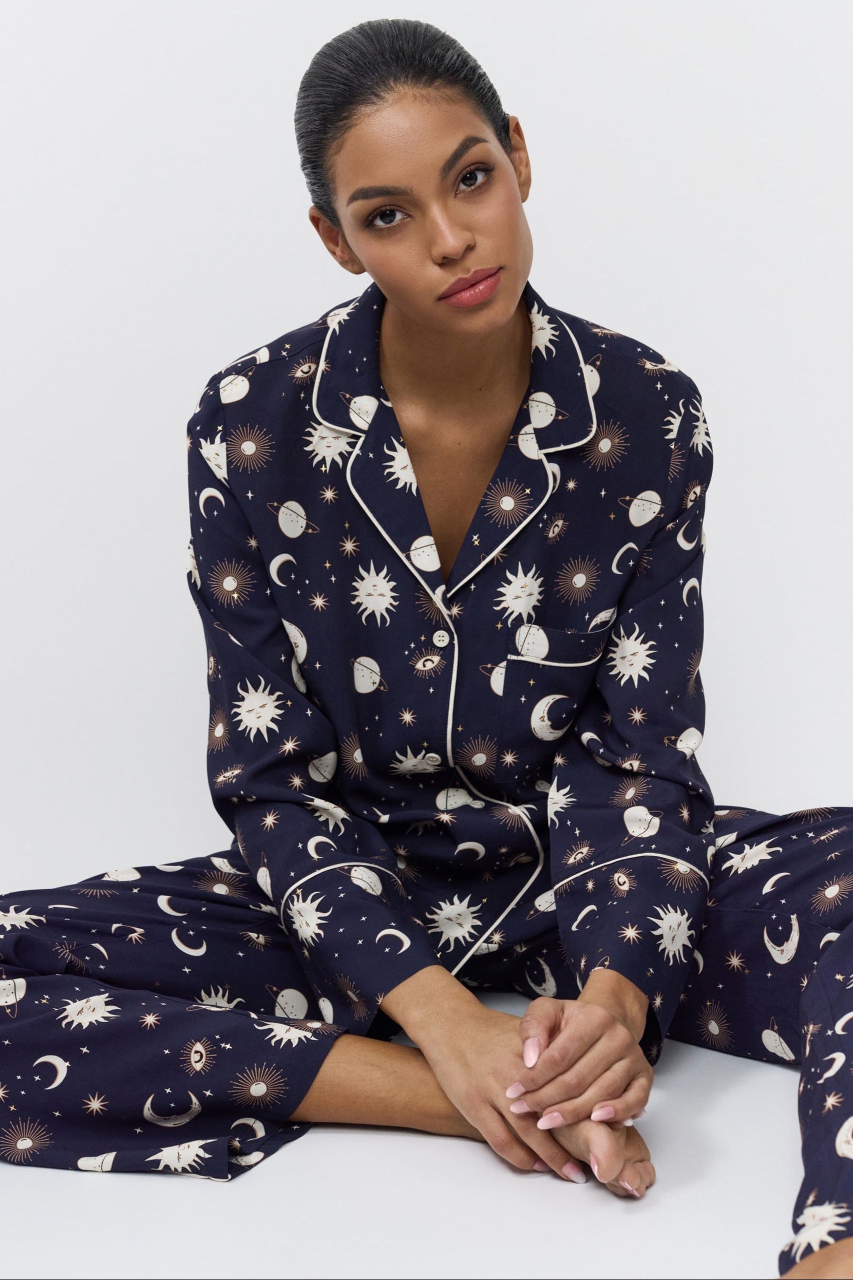 Woman wearing a navy blue pajama set with pattern on a white background