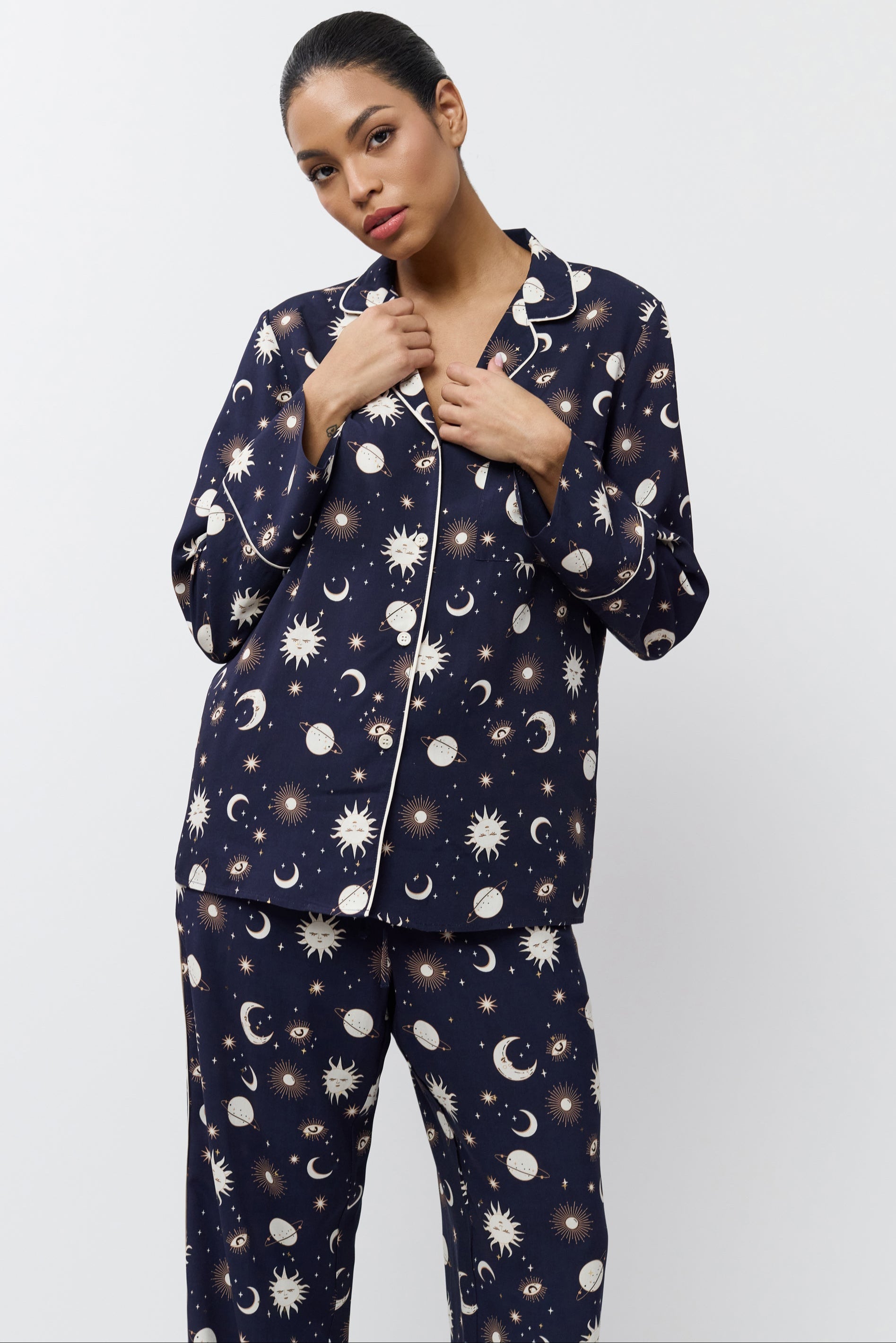 Woman wearing a navy blue pajama set with pattern on a white background