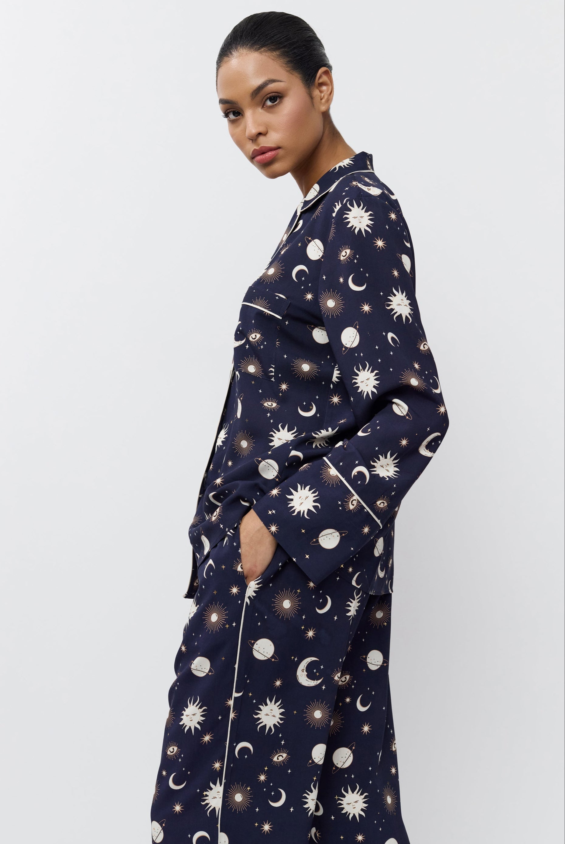 Person wearing a navy pajama set with pattern on a white background