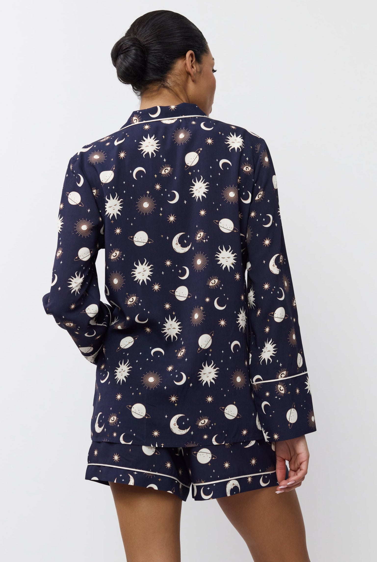 Person wearing a navy pajama set with celestial print on a white background