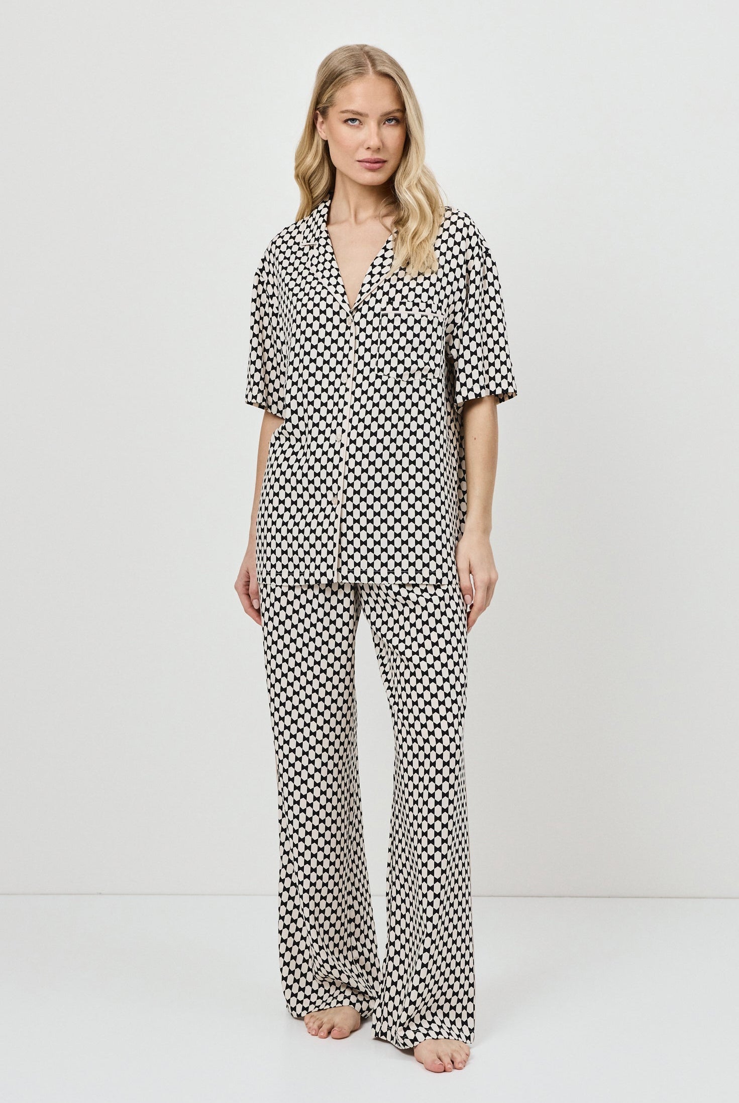 Woman wearing a patterned pajama set on a white background.