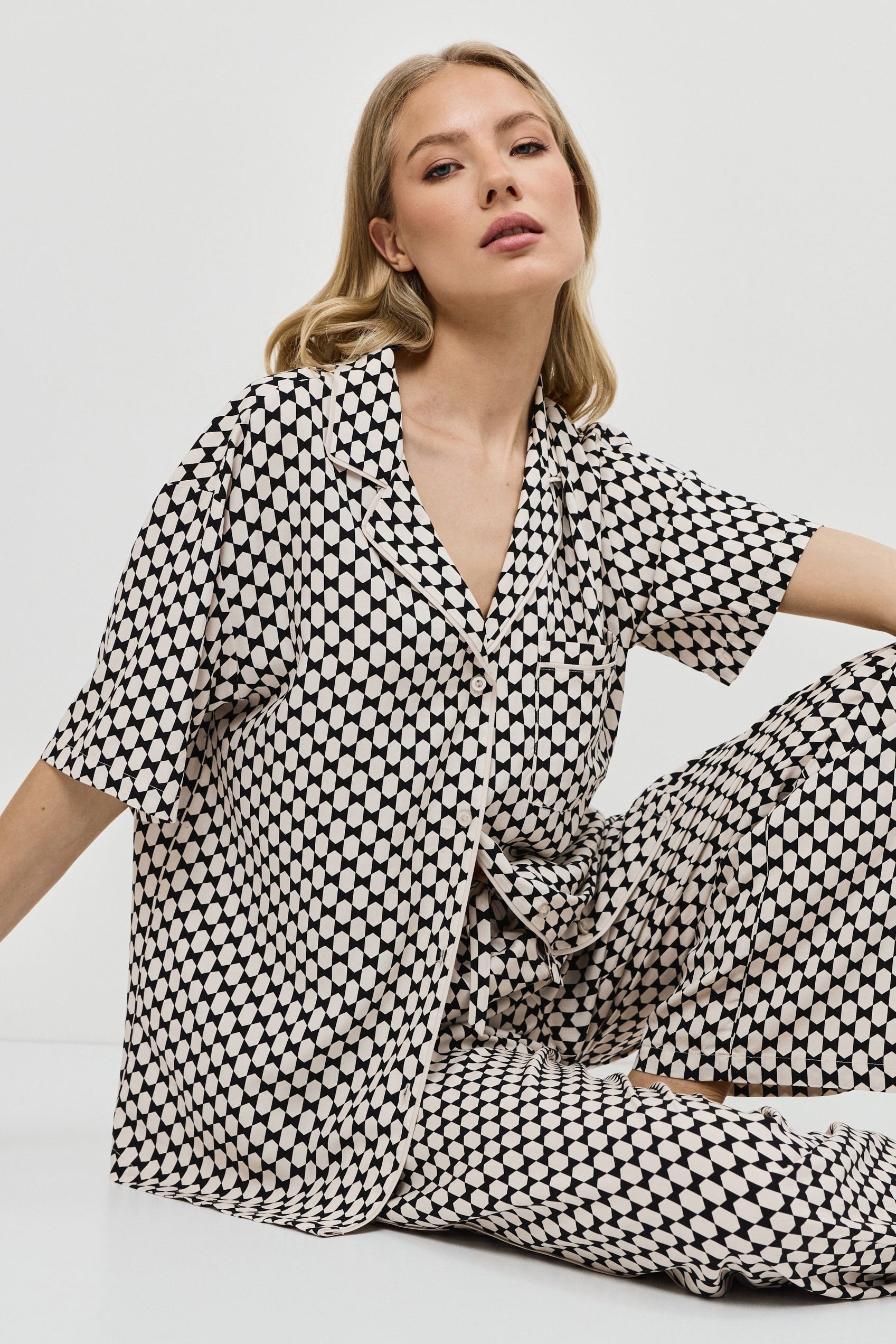 Woman wearing a patterned pajama set on a plain background