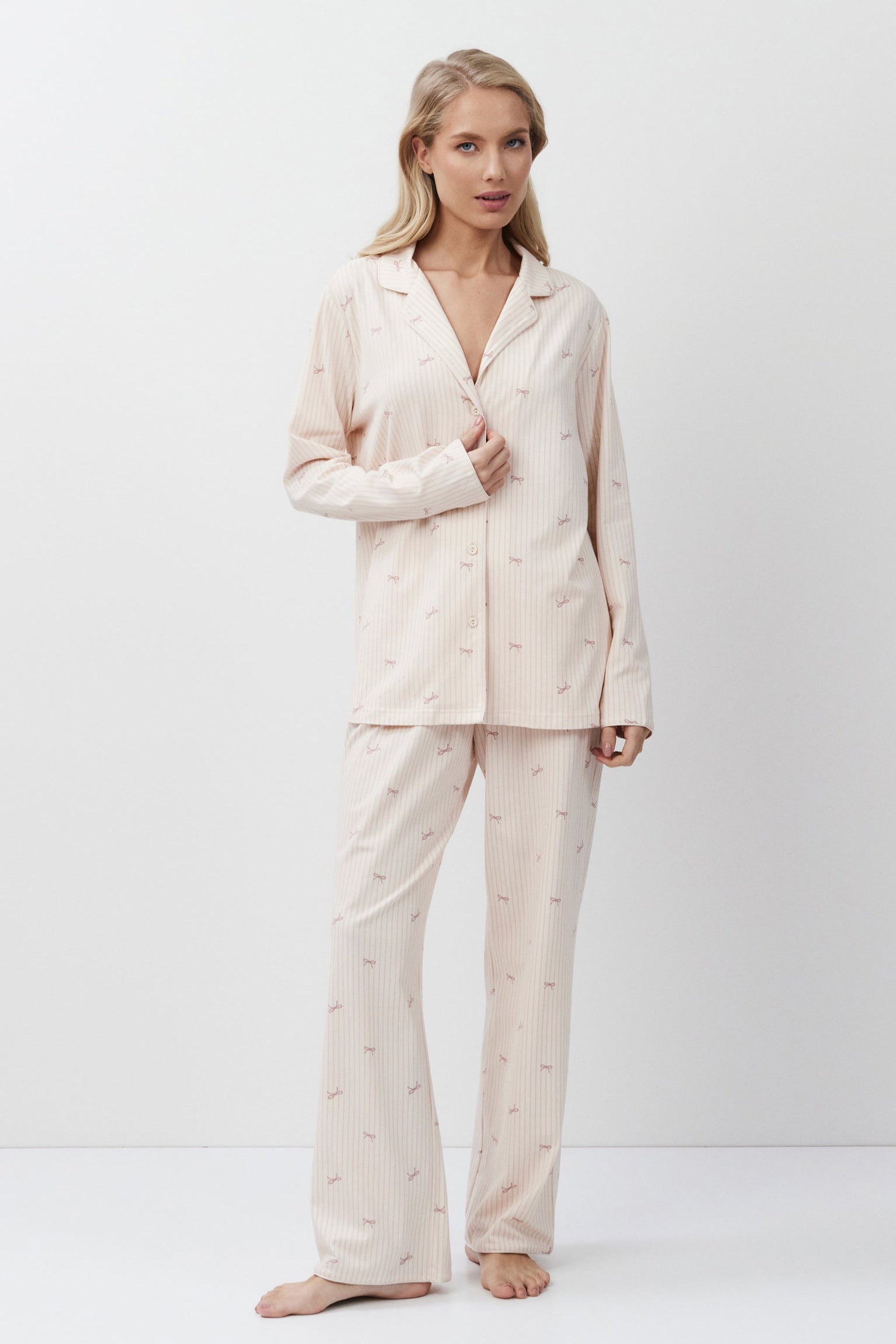 Woman wearing a pink-colored pajama set on a white background