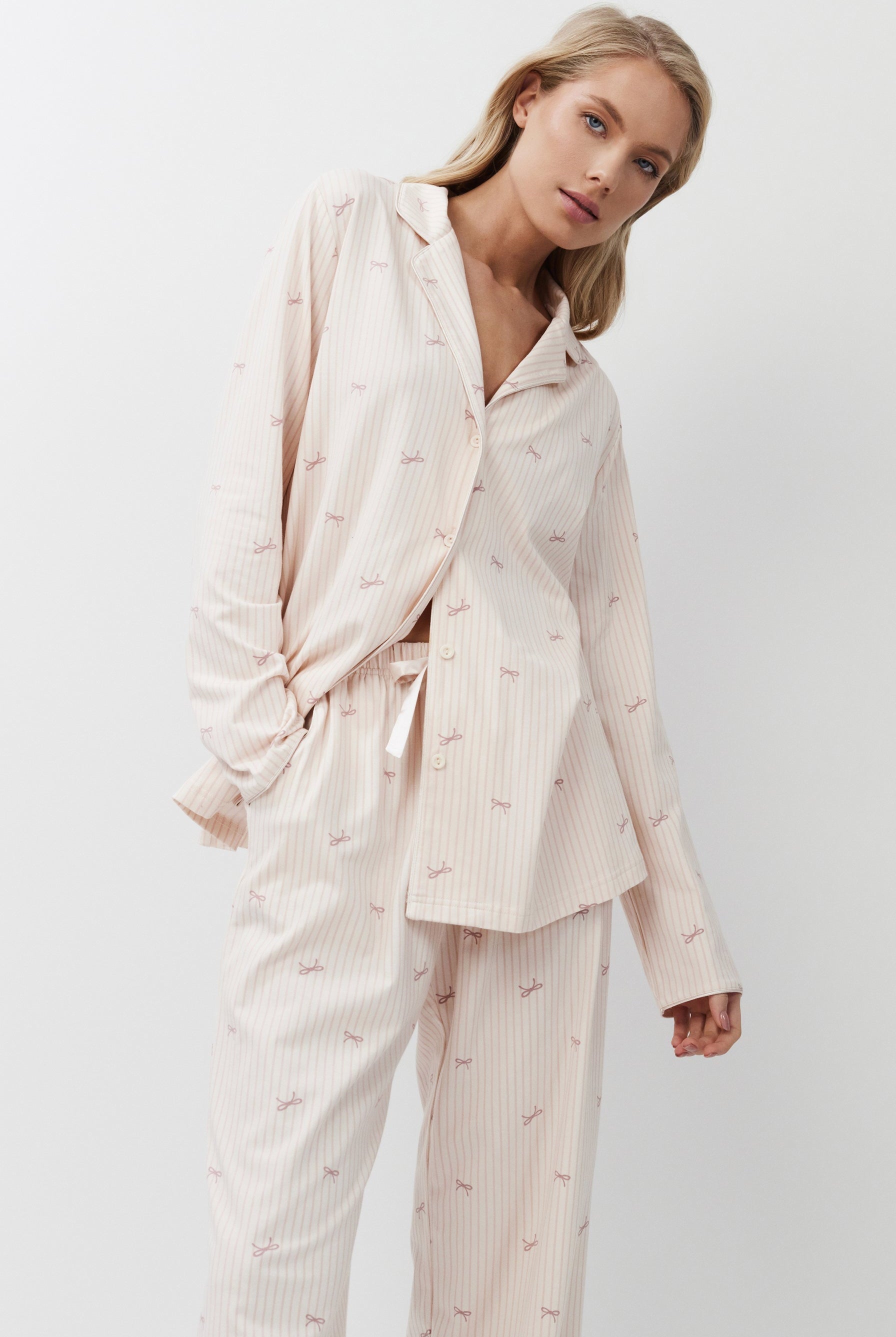 Woman wearing a light pink pajama set against a white background