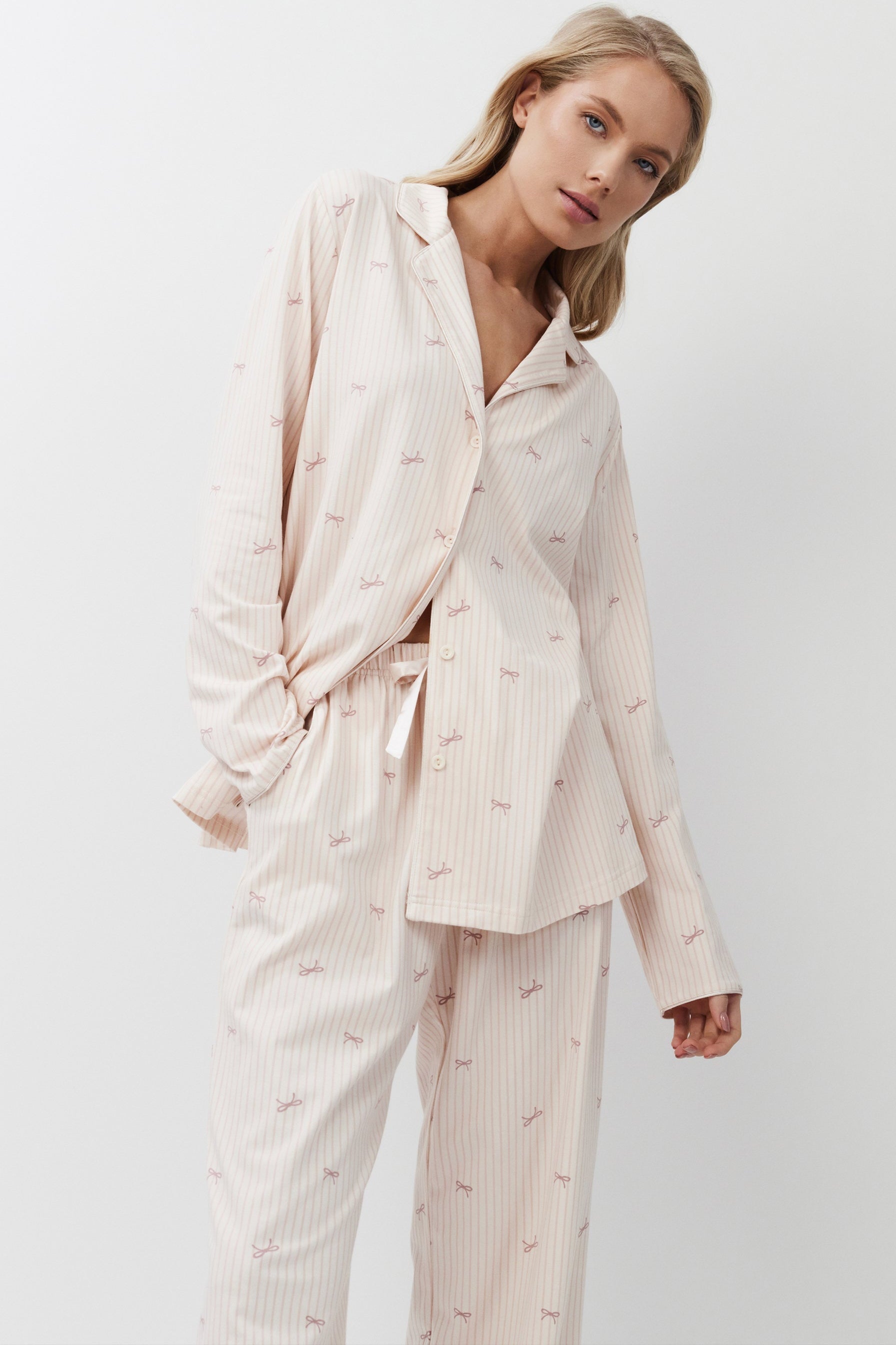 Woman wearing a light pink pajama set against a white background